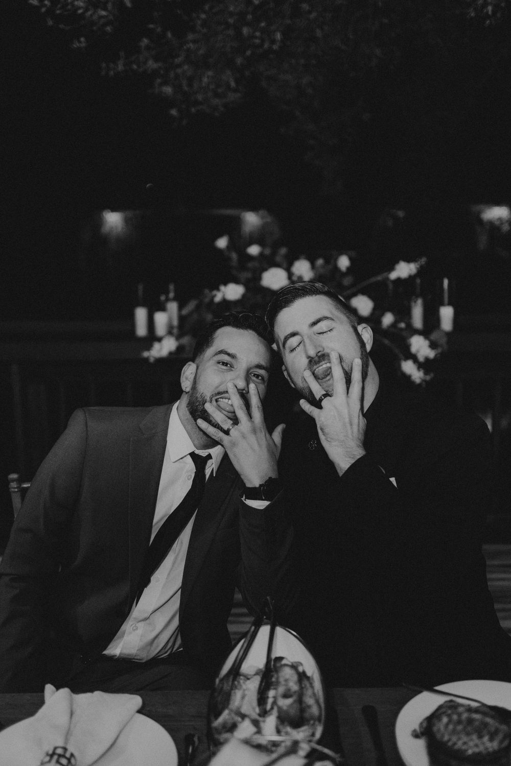 Candid black and white photo of guests laughing during wedding reception.