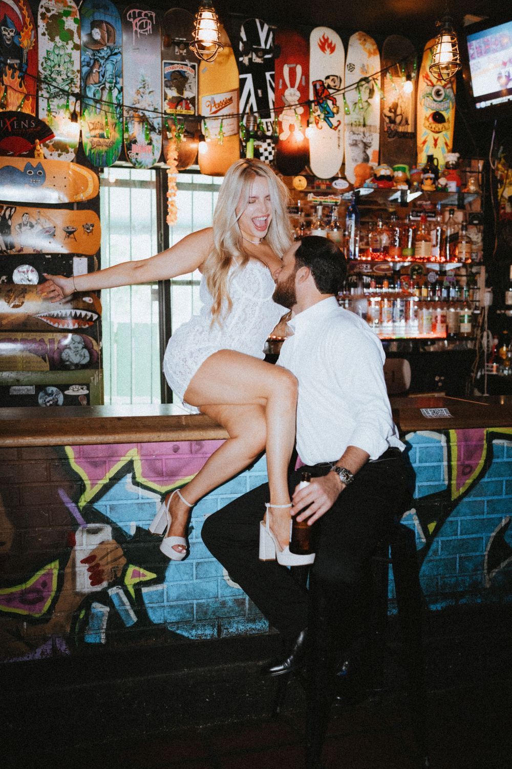 A spirited dance sequence unfolds in a rustic bar setting with colorful wall art and ambient lighting.