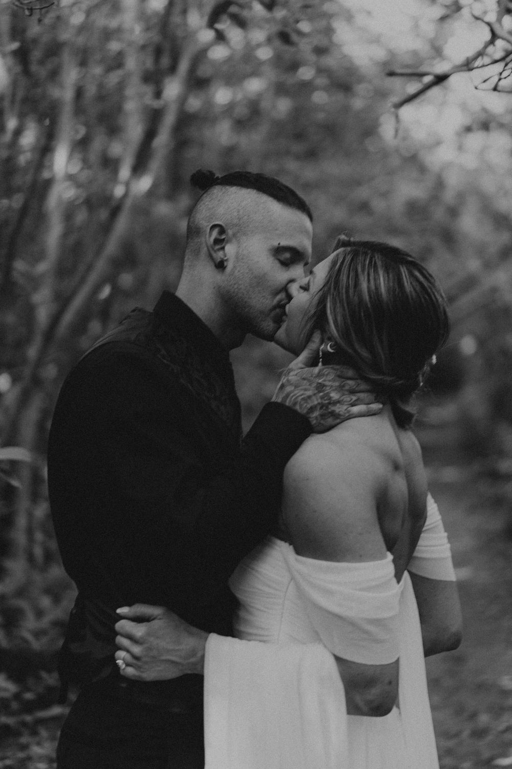Intimate black and white portrait of a couple sharing a romantic moment in nature.