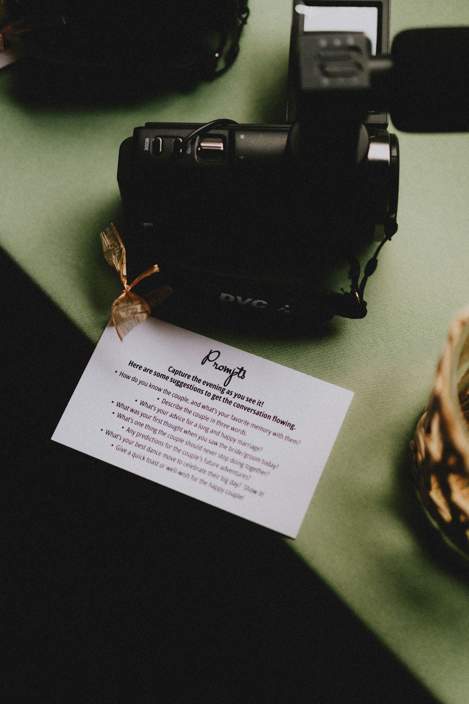 Blurred business cards and camera equipment on a green surface in moody lighting.