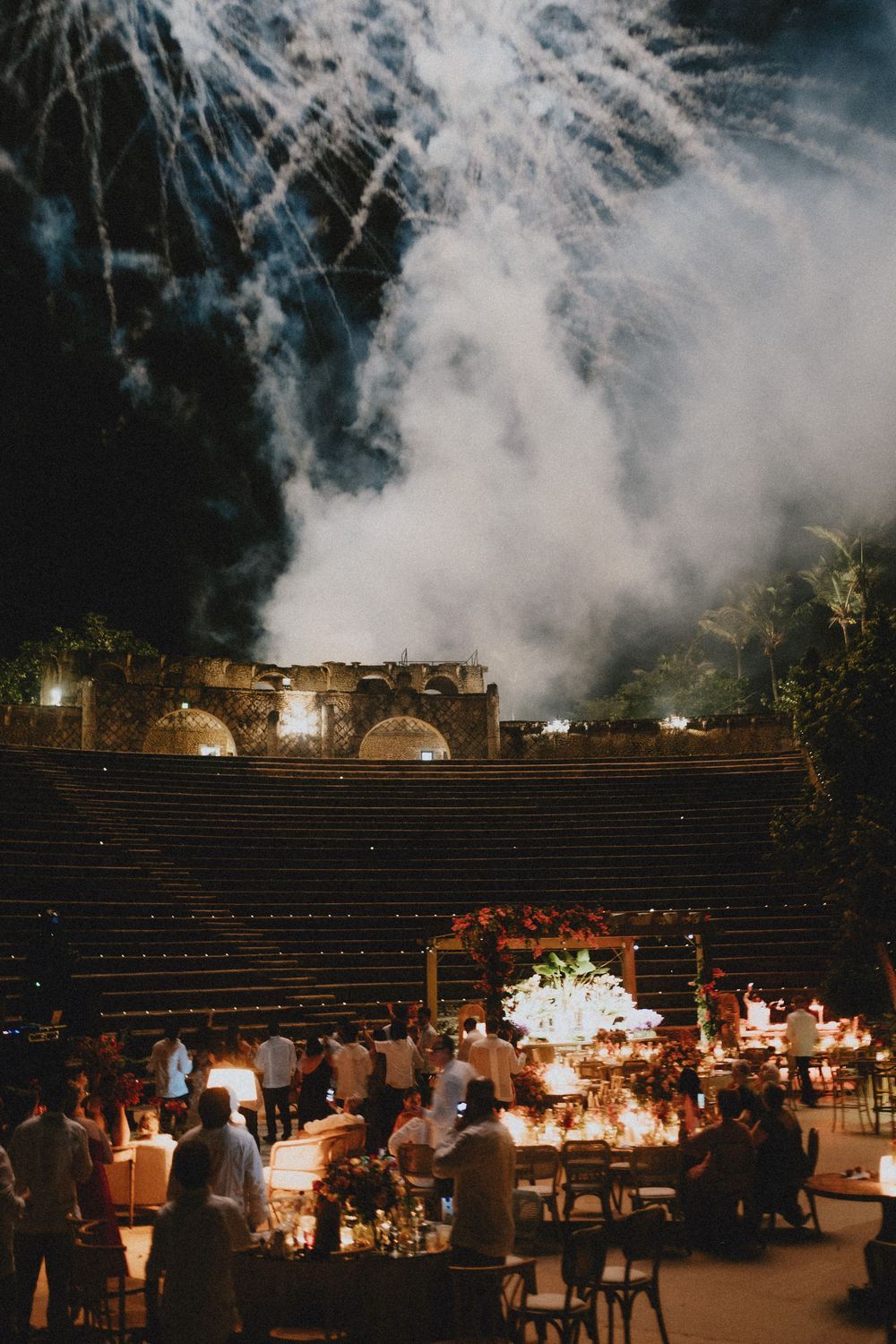 Evening outdoor wedding reception with twinkling lights and misty atmosphere.