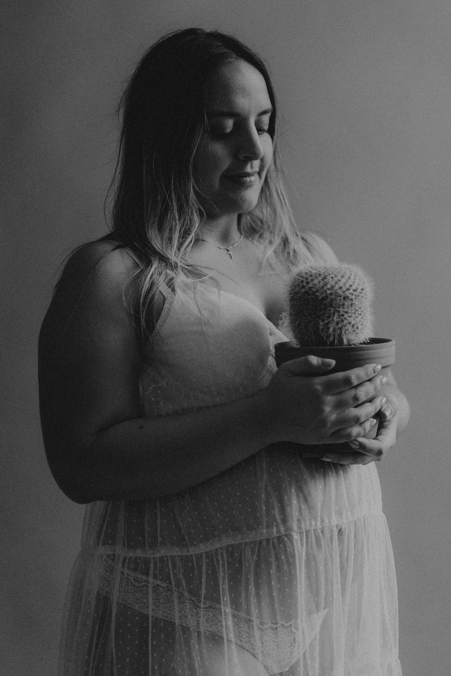 A series of black and white photos showing someone in a white dress holding a cactus plant against a dark background.