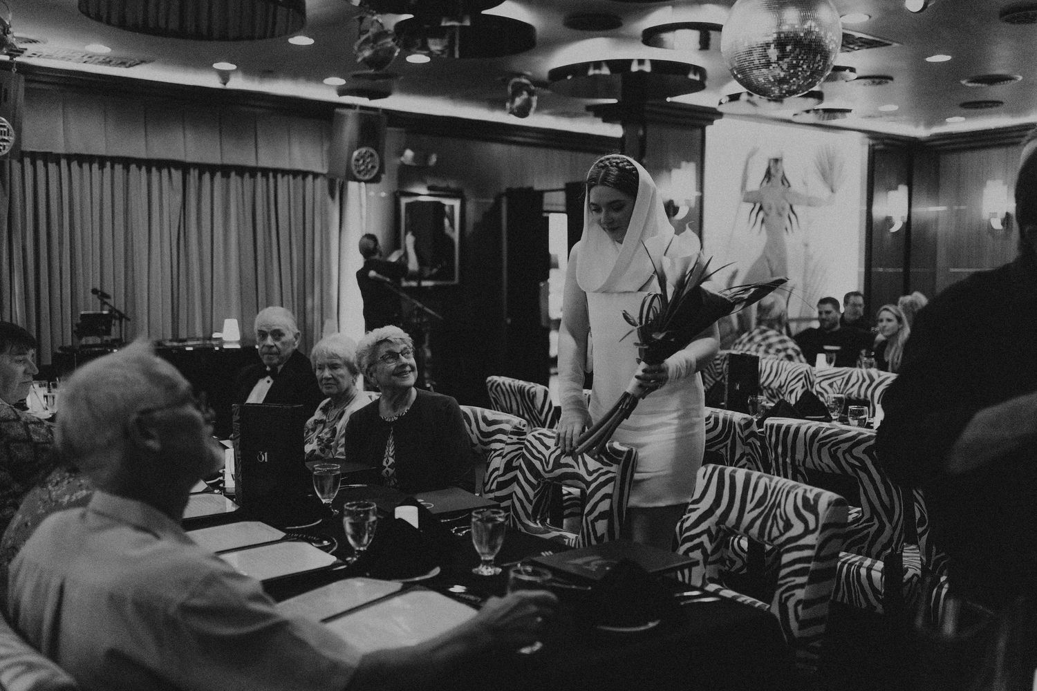Wedding reception guests gathered in retro lounge with zebra print furniture in black and white.