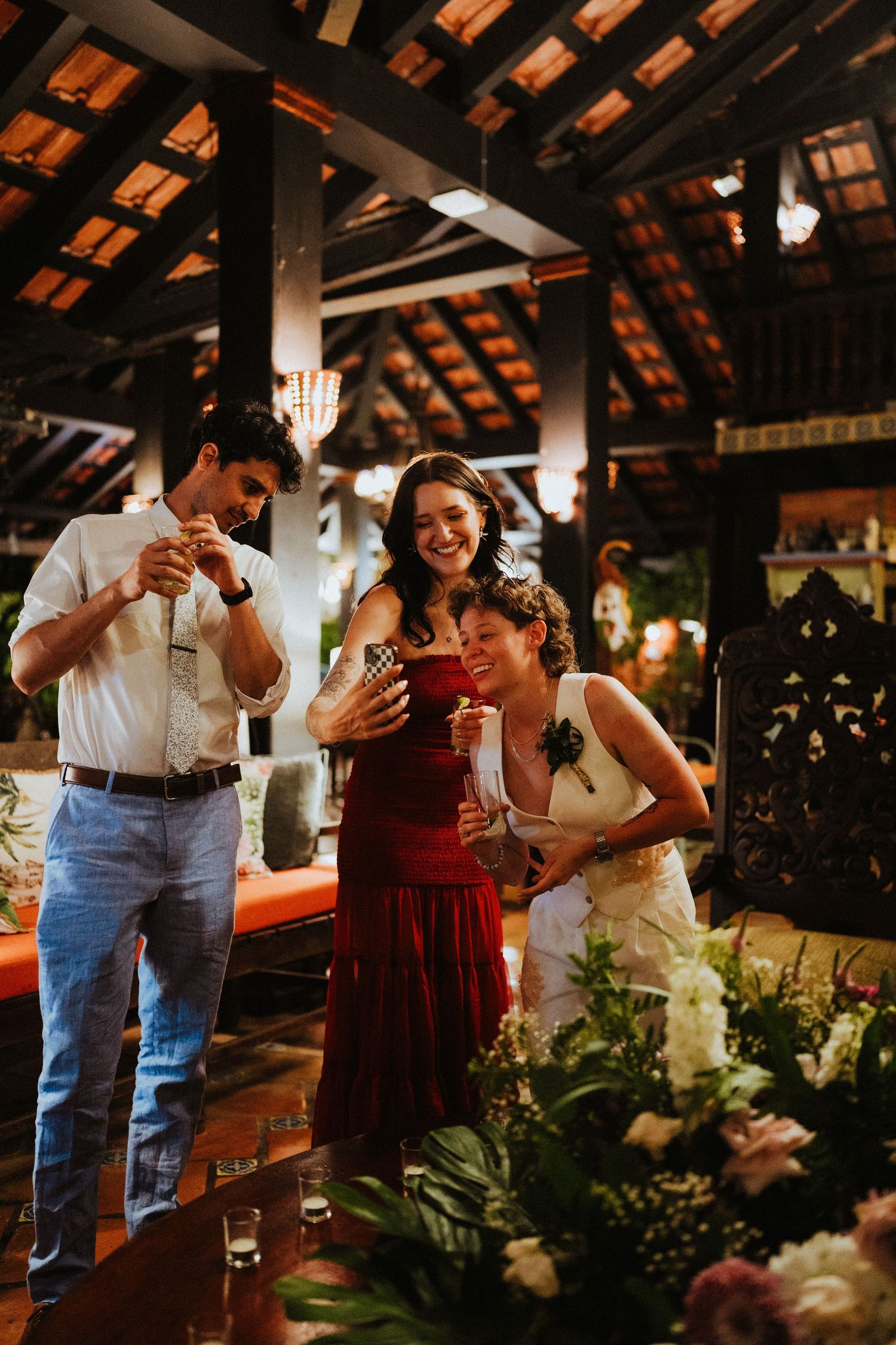 Three guests laughing and celebrating together at an elegant indoor wedding reception venue.