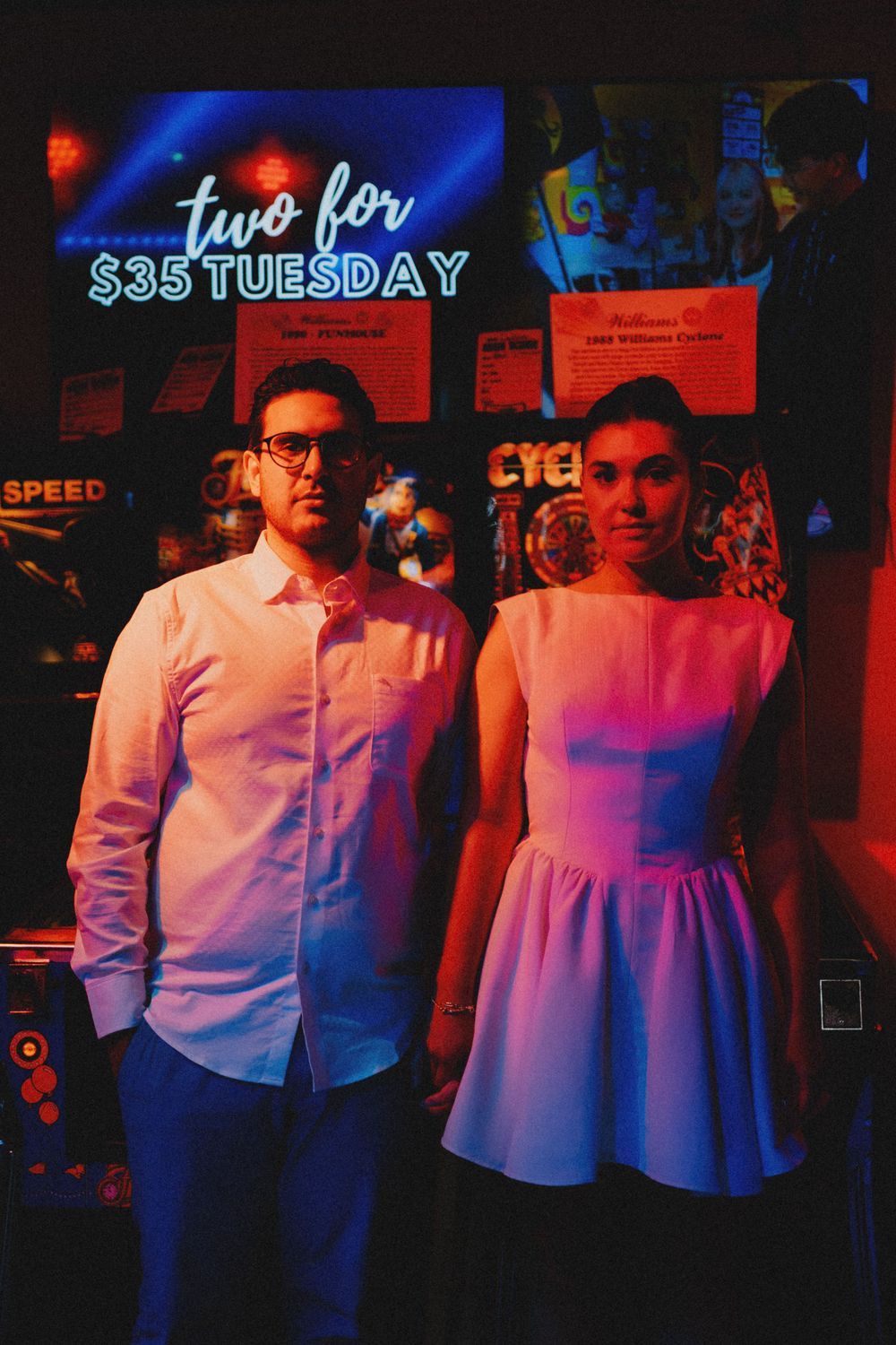 People pose in front of neon lights creating a vibrant red and blue atmosphere.