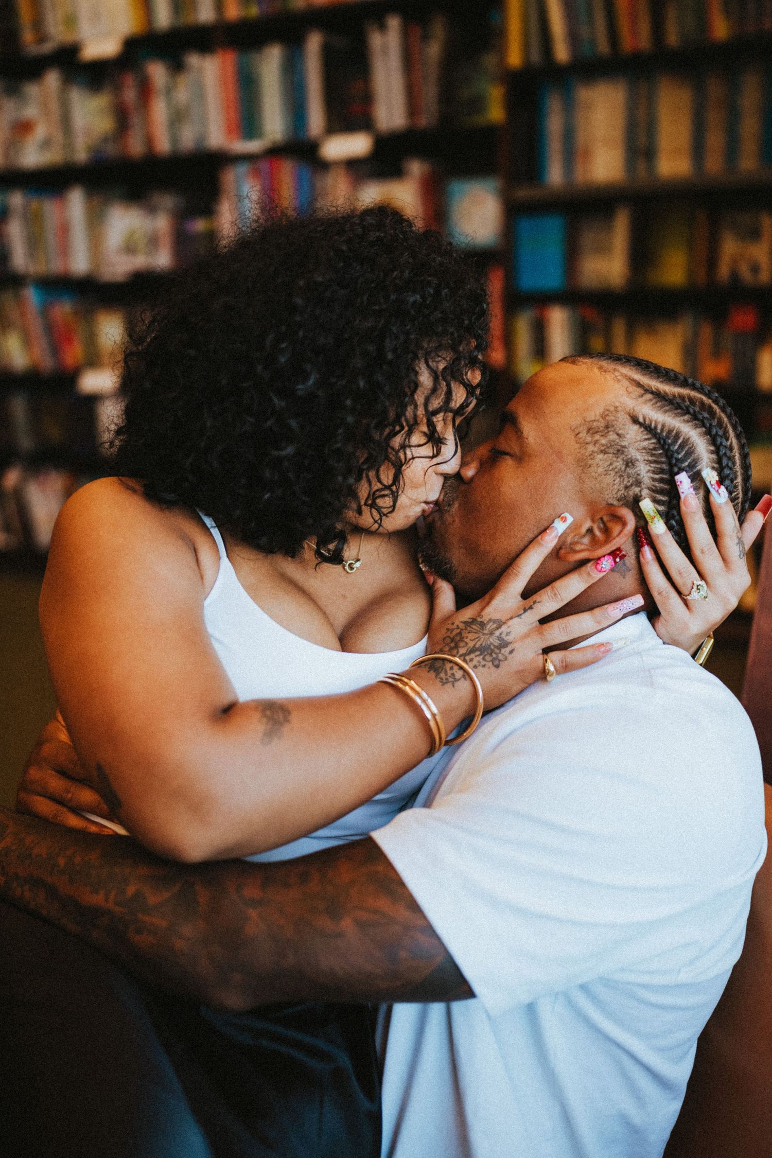 Couple sharing a passionate kiss in front of colorful bookstore shelves.