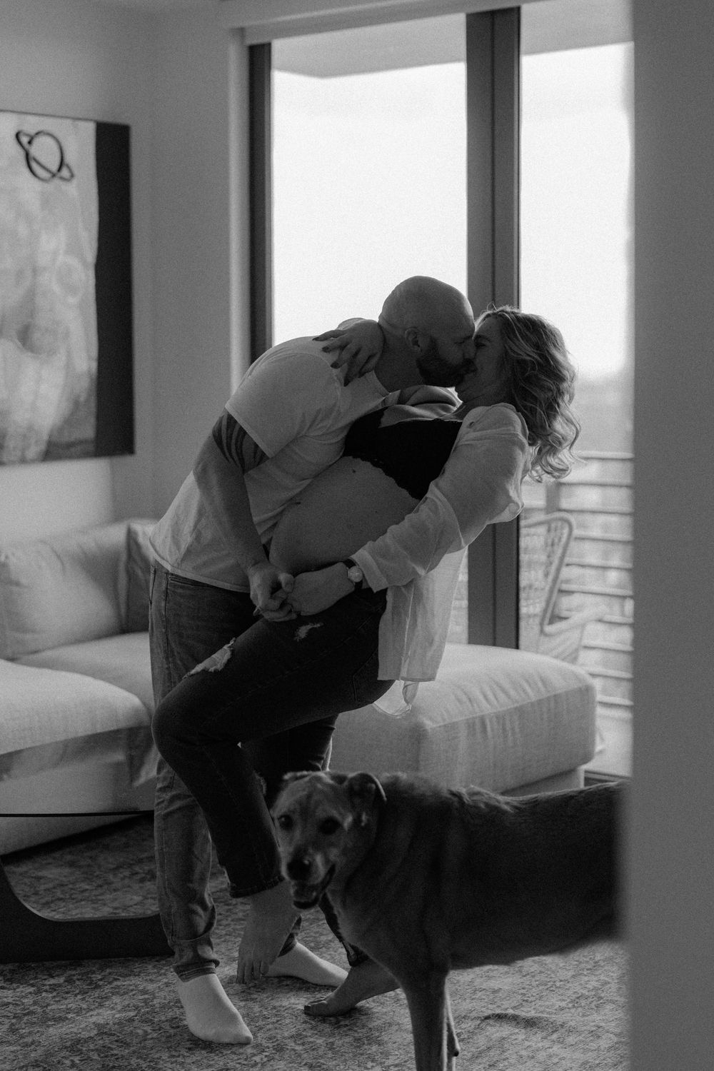Black and white photo series showing a person in casual clothing interacting with a dark-colored dog on a couch.