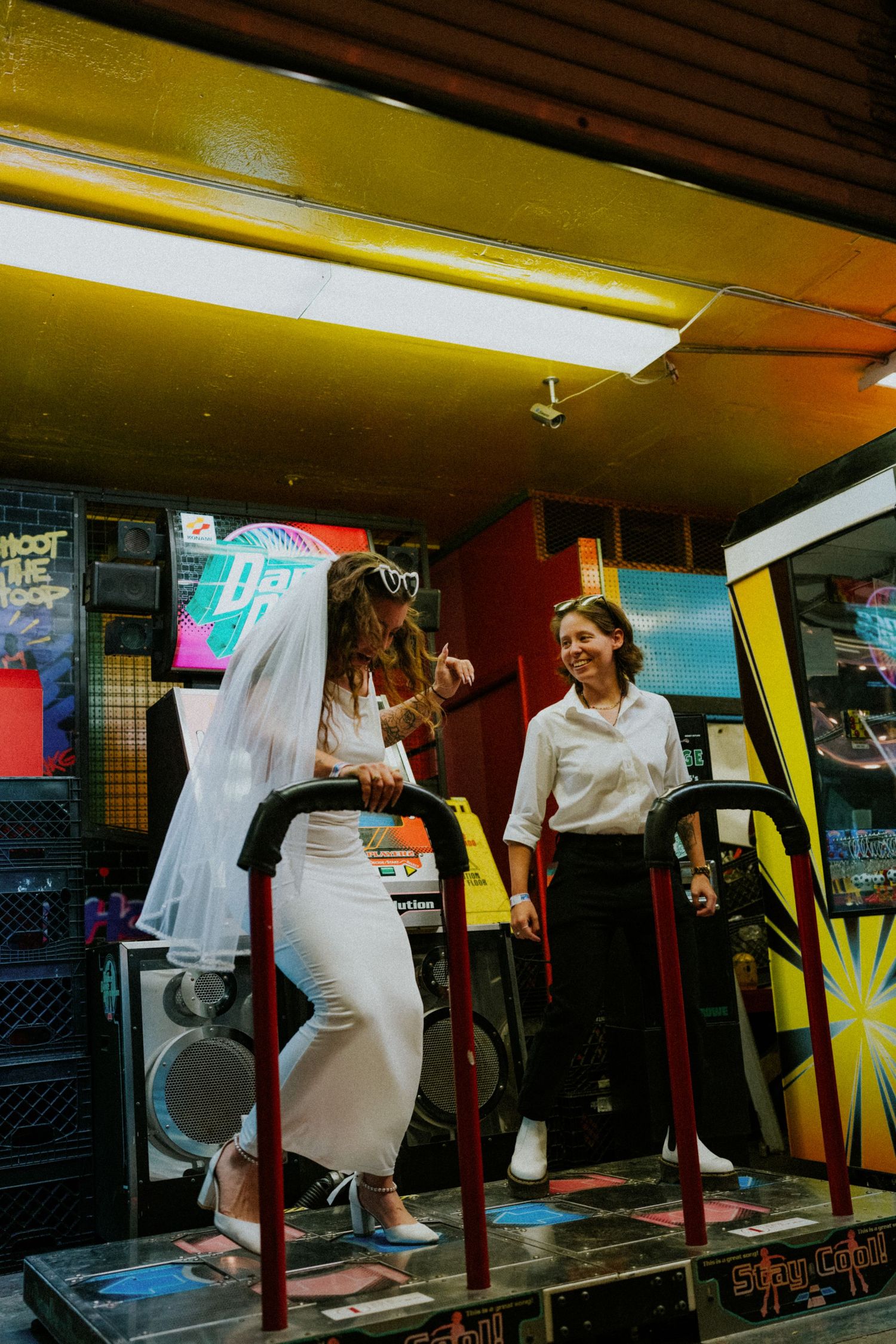 A series of arcade dance game machines in a dimly lit arcade with neon lighting and colorful graphics on display.