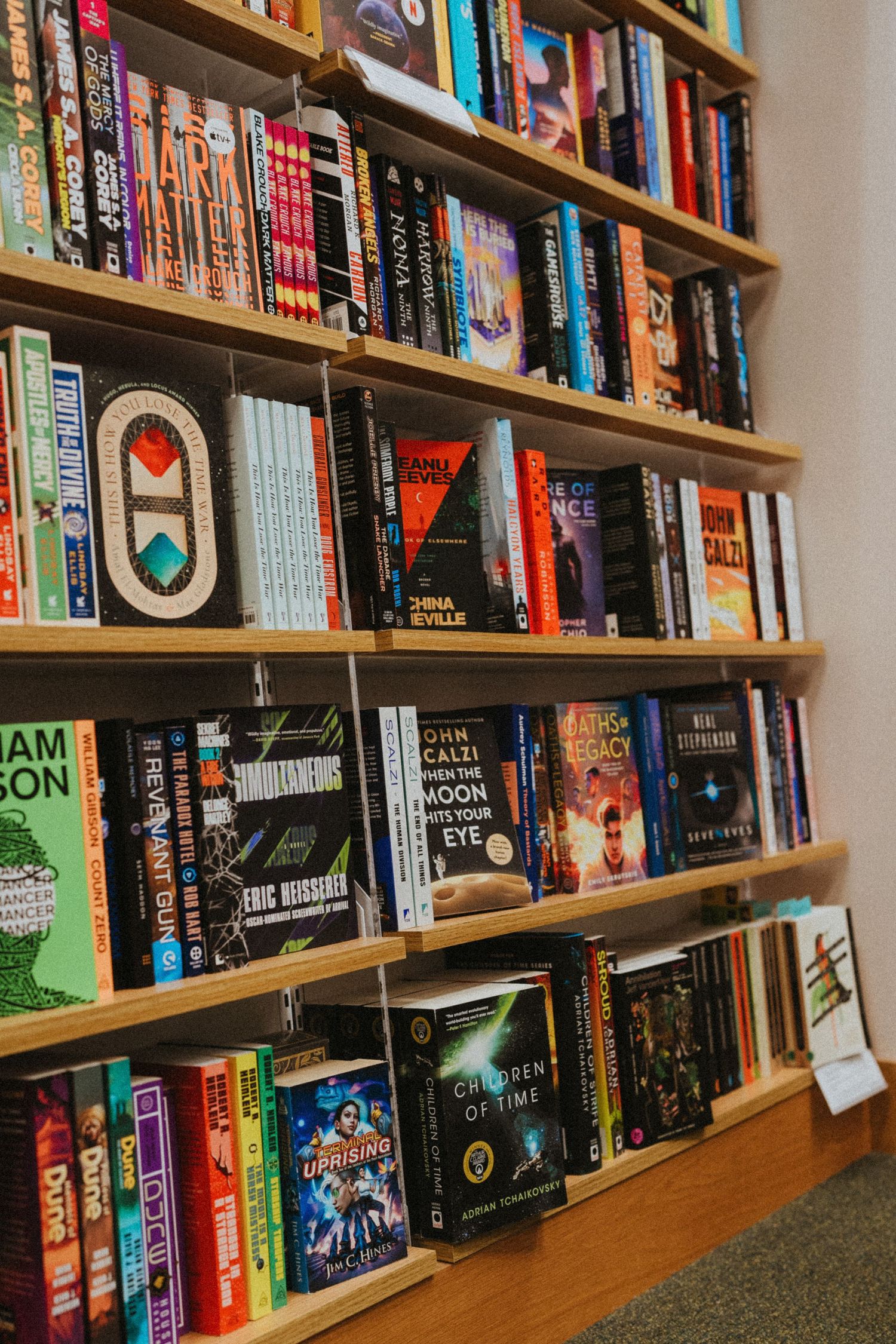 Colorful bookstore shelves filled with science fiction and fantasy novels in a well-lit store.