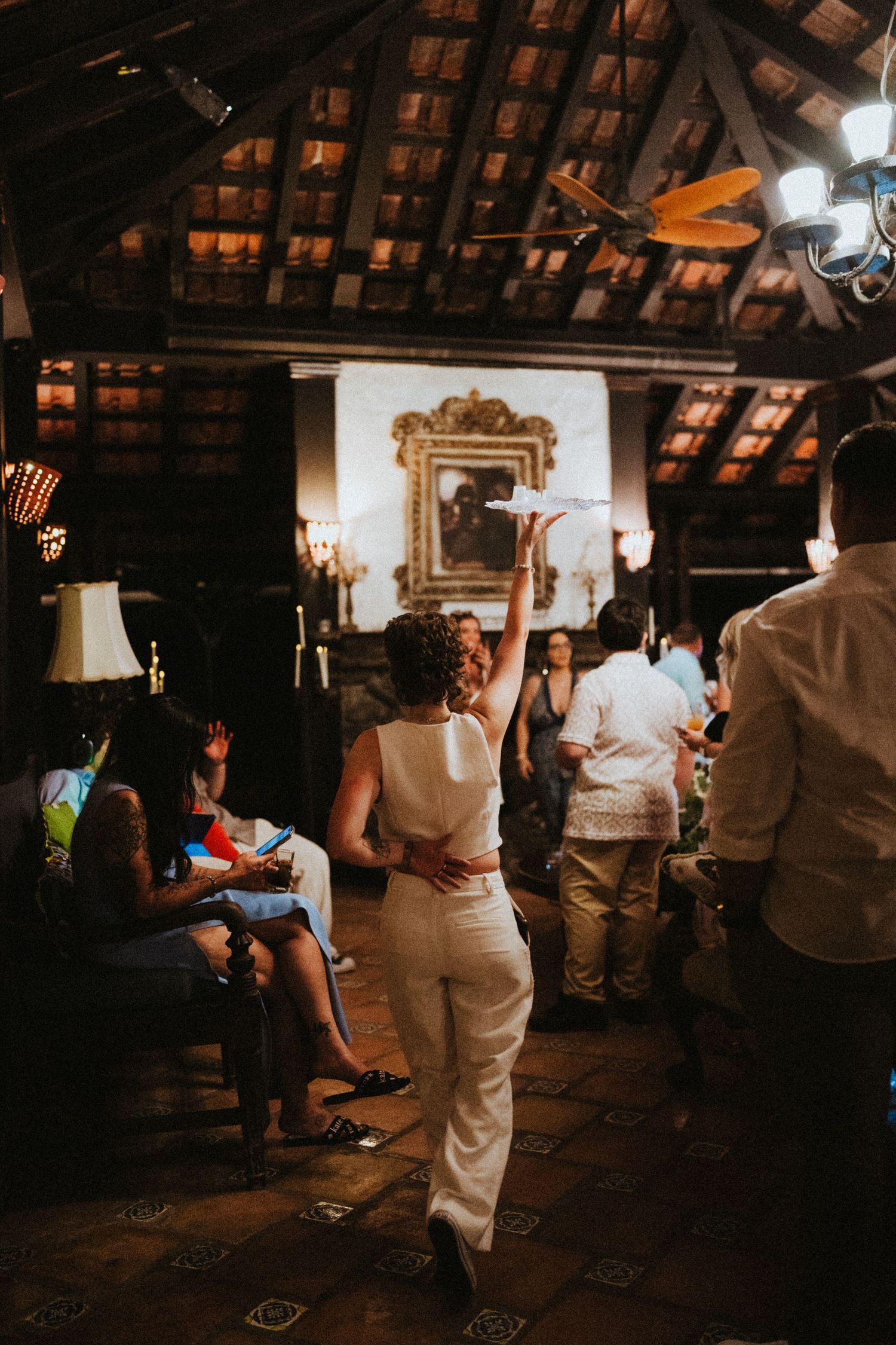 Woman in white outfit dancing at an elegant indoor venue with rustic wooden ceiling and warm ambient lighting.