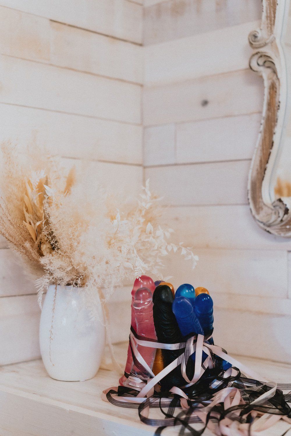 White ceramic vases with dried pampas grass arranged on a shelf with sneakers below.