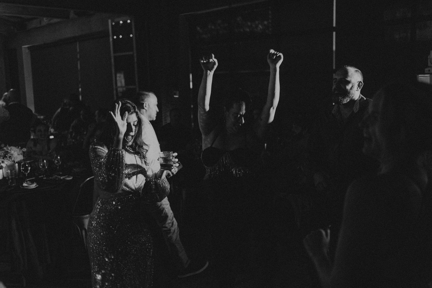 Black and white photo of wedding guests dancing and celebrating on the dance floor at a reception.