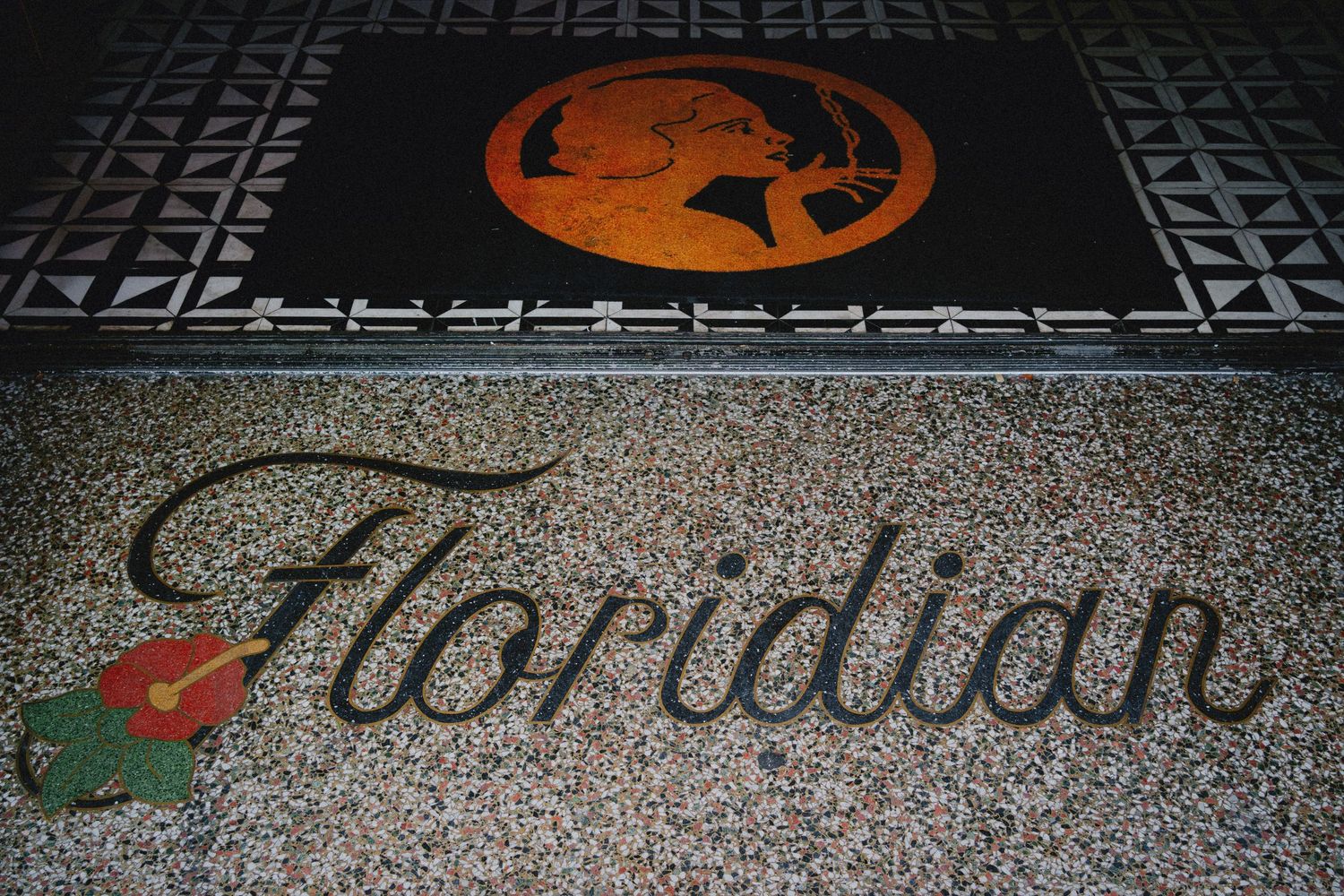 Floridian restaurant logo on terrazzo floor with orange cameo emblem and colorful floral accent.