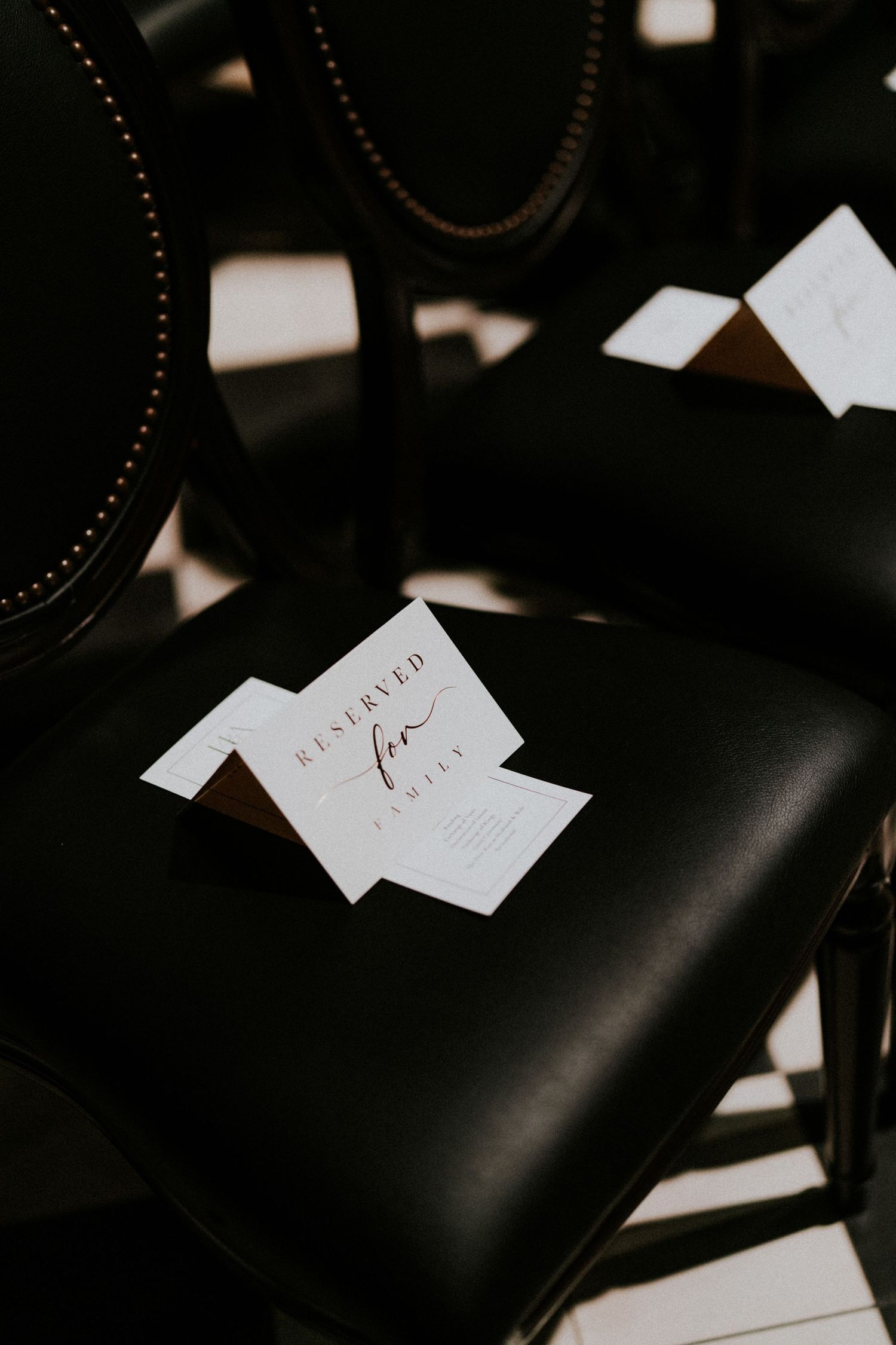 Elegant black leather chair with a white reserved for family card at a wedding ceremony venue.