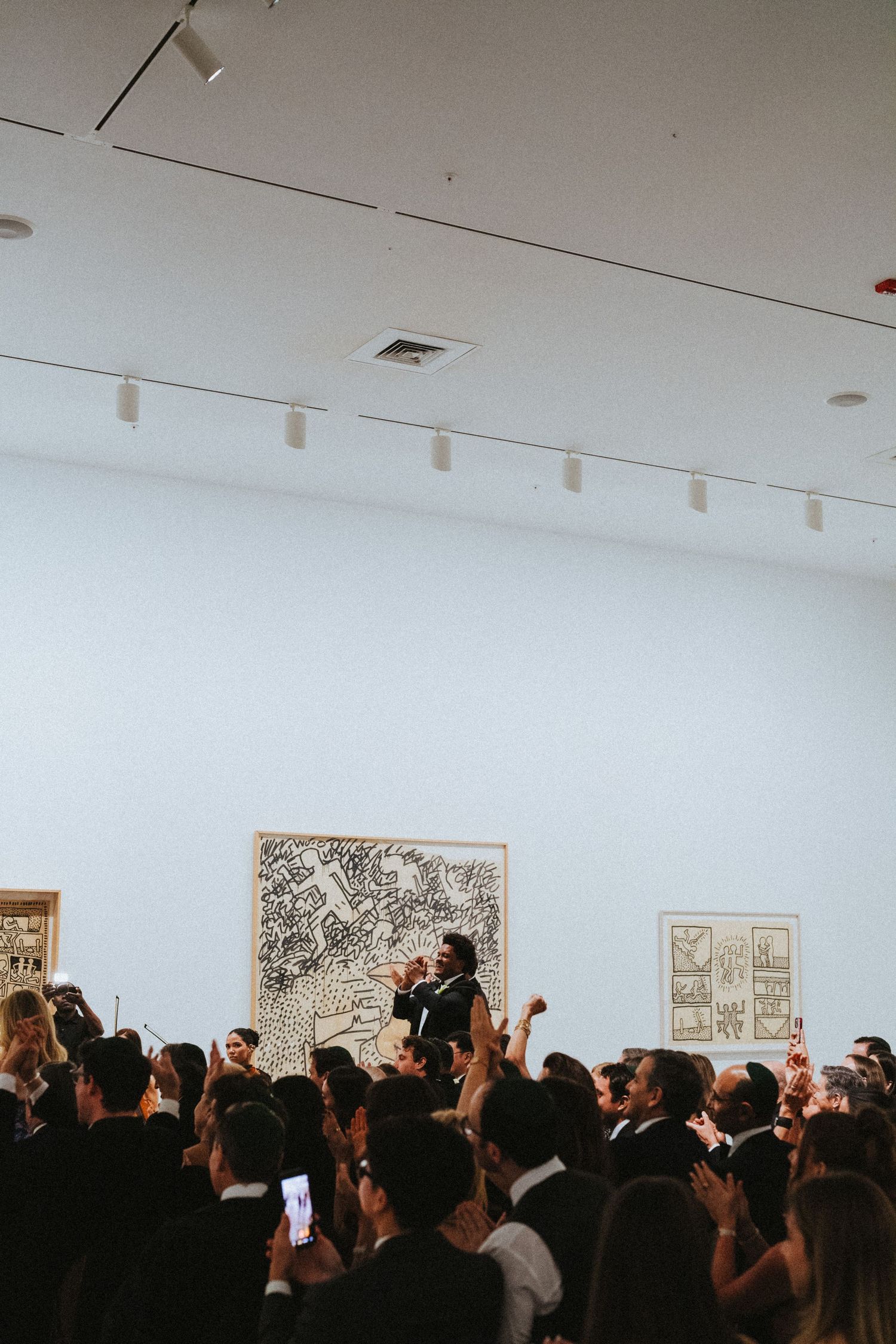 Elegant crowd of guests in formal attire gathered in an art gallery during a sophisticated evening event.