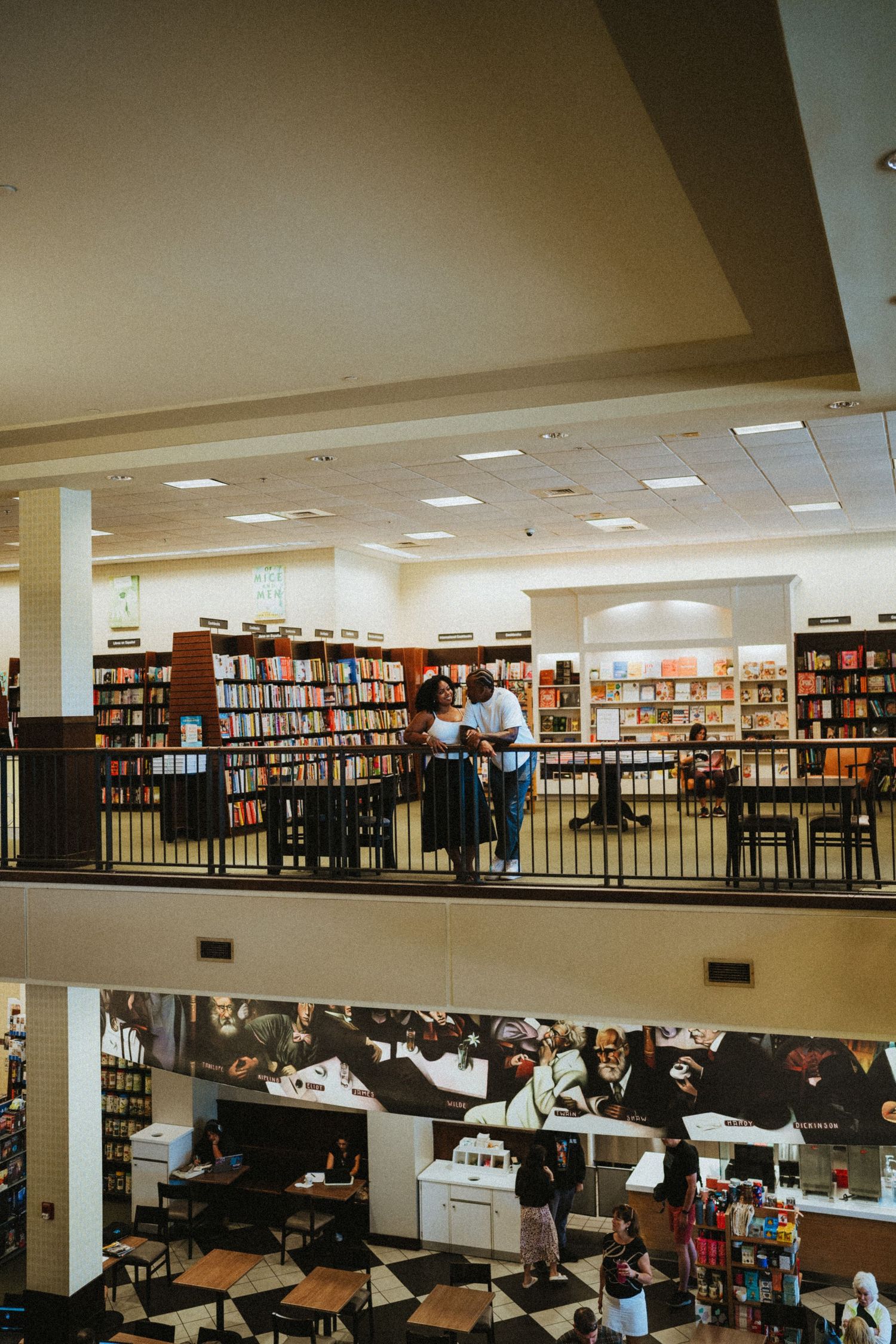 Couple sharing a romantic moment on the second floor balcony of a large two-story bookstore.