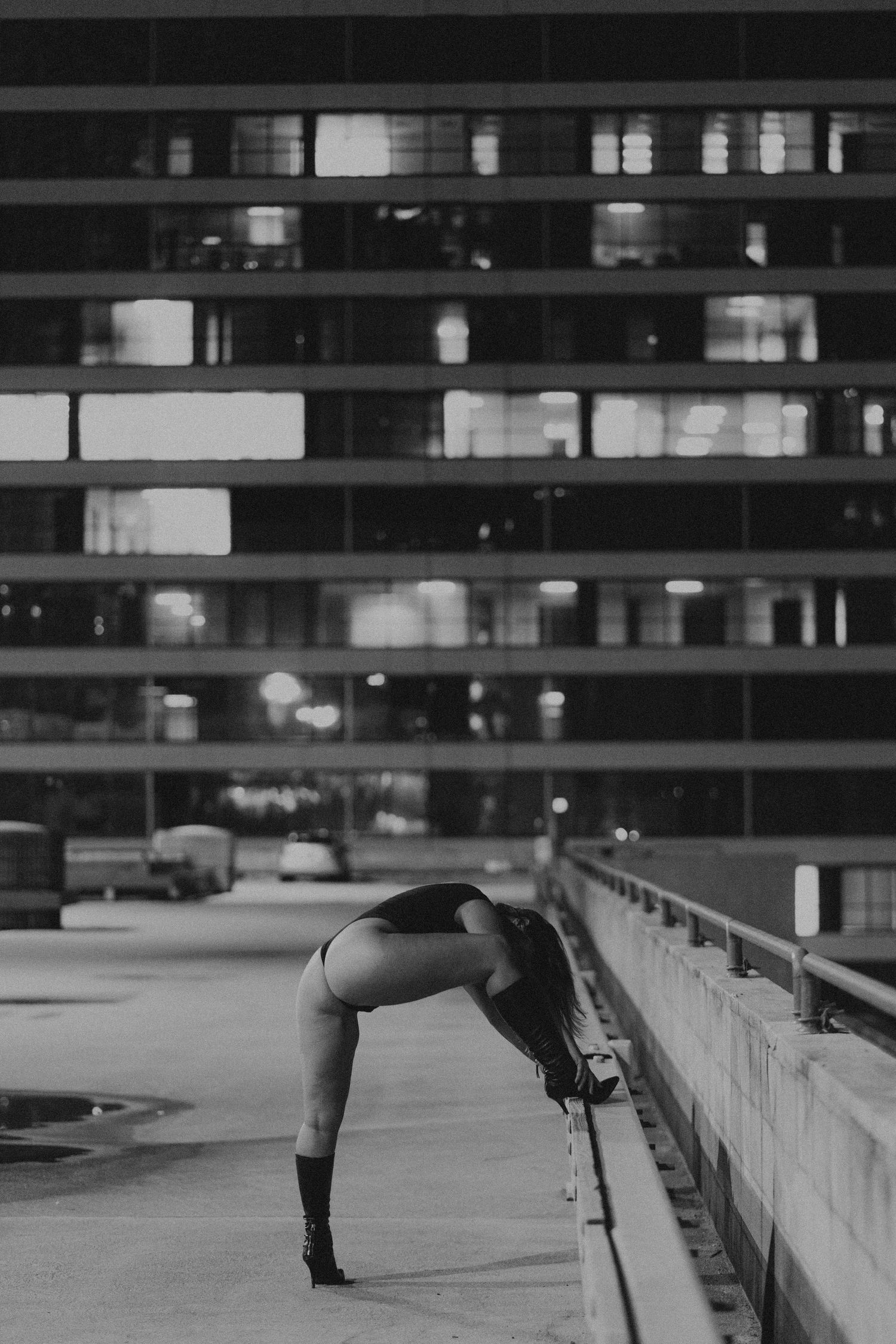 Black and white photo of person in athletic pose on parking structure.