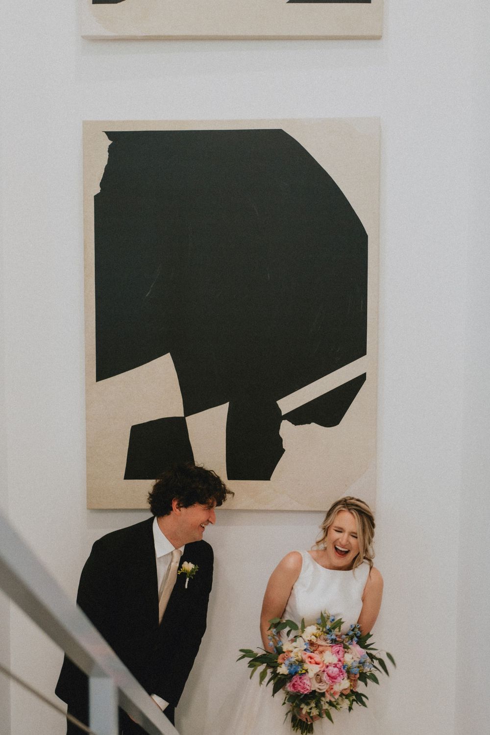 Modern wedding portrait with minimalist black and white artwork in the background.