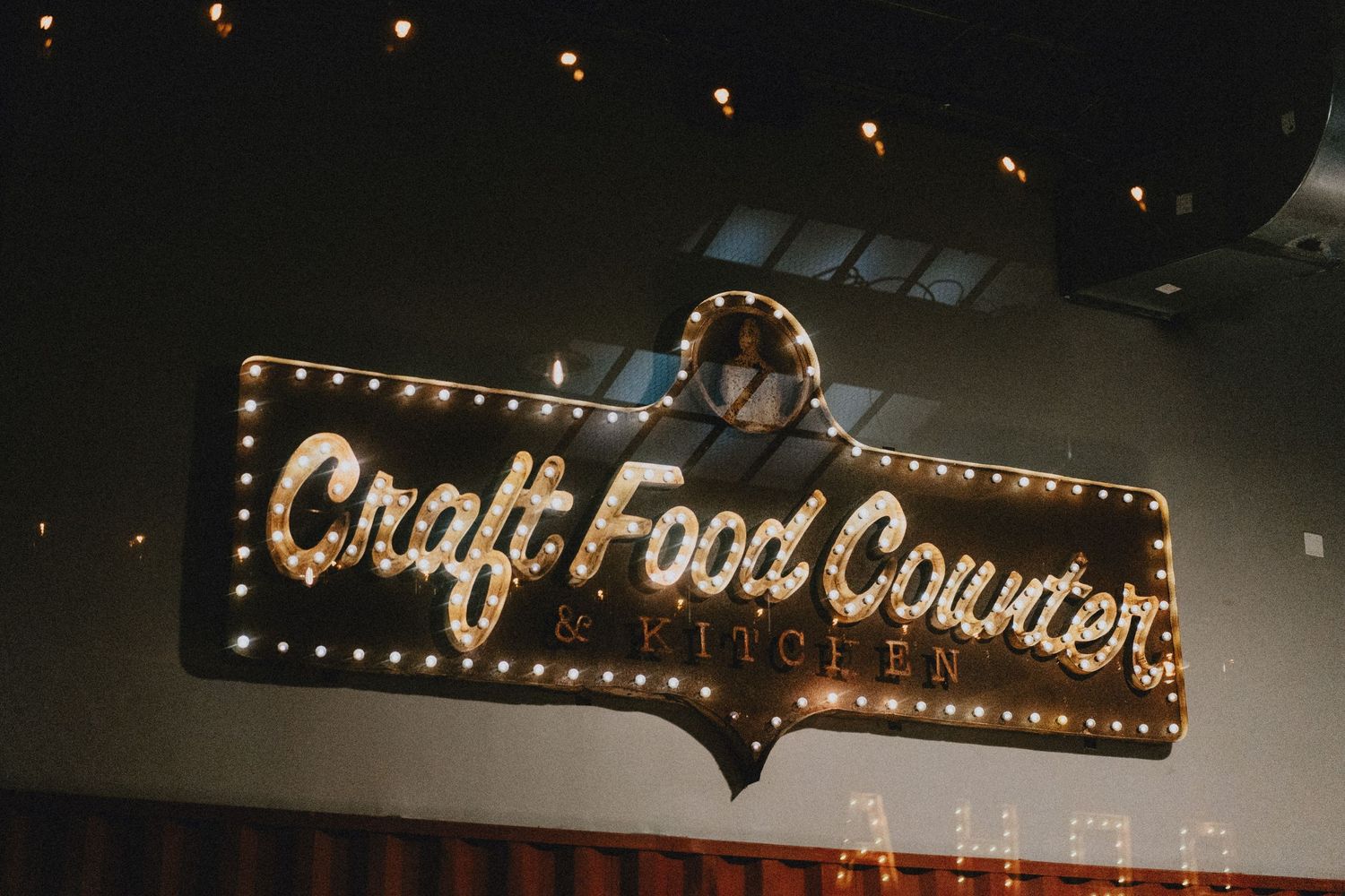 Illuminated Craft Food Counter Kitchen sign with vintage bulb lights at a wedding venue.