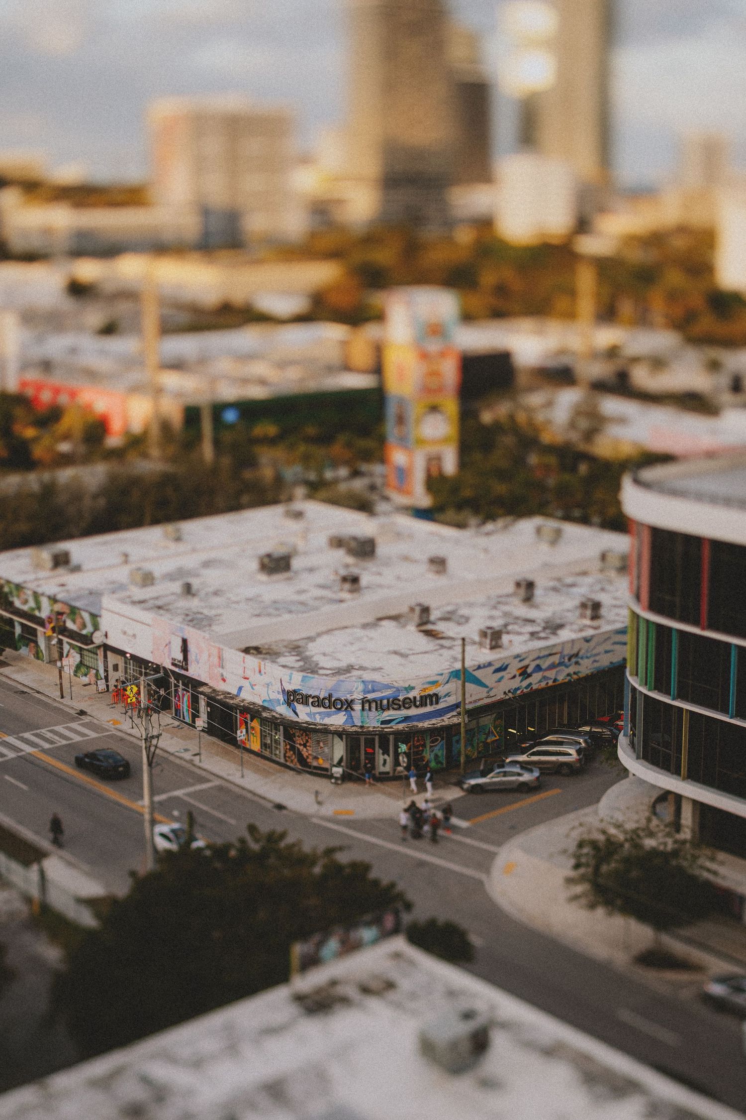 Aerial tilt-shift view of Paradox Museum building in Miami urban cityscape at golden hour.