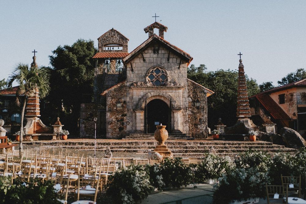 Panoramic view of a rustic stone church with outdoor wedding ceremony setup.