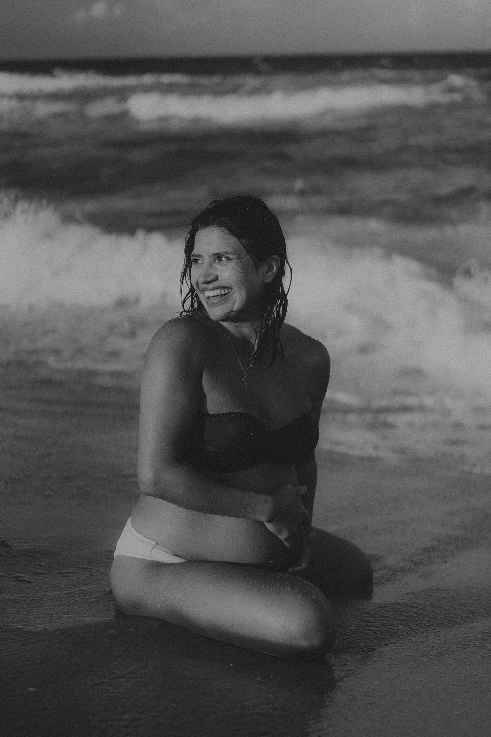 A black and white photo series showing a person lying on a beach with waves in the background.