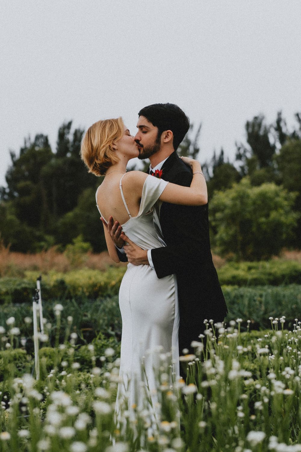 Romantic moment captured in a field of white wildflowers on a sunny day.