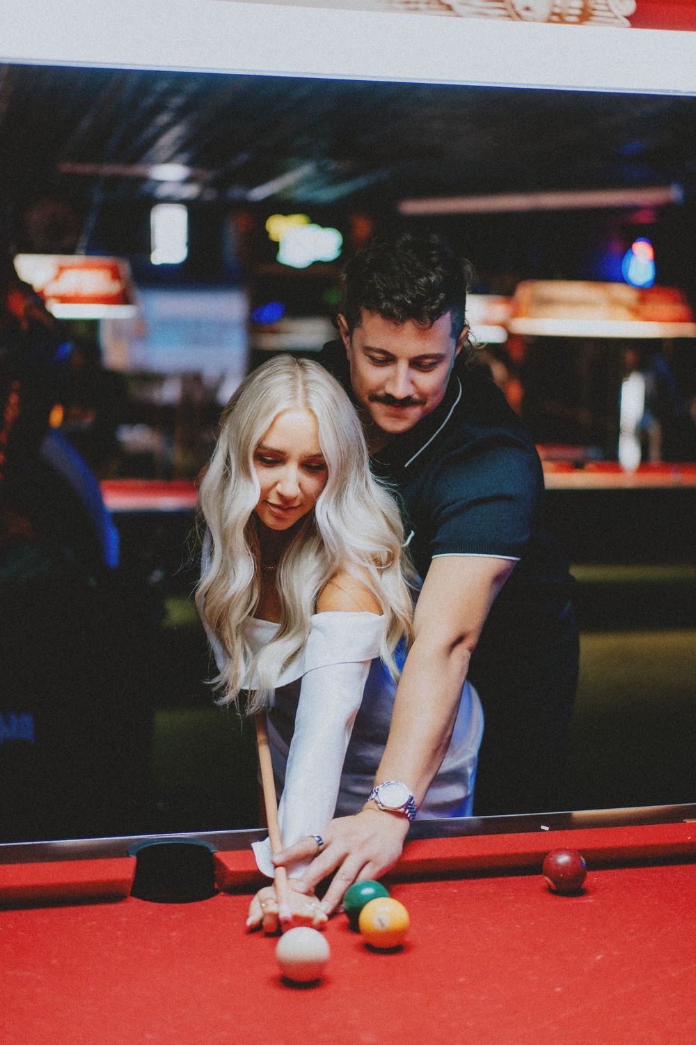 Two people enjoying a game of pool together in a bar setting.
