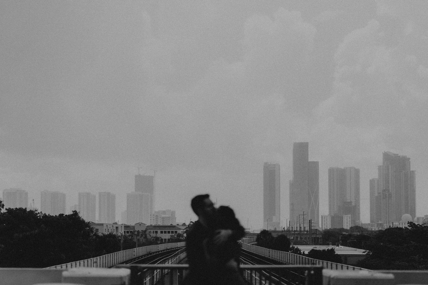Misty cityscape showing dark silhouette of skyline against grey sky.