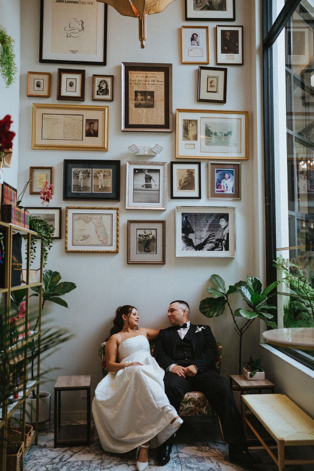 A cozy interior space decorated with framed photos and artwork on the wall features a quiet moment between a couple.