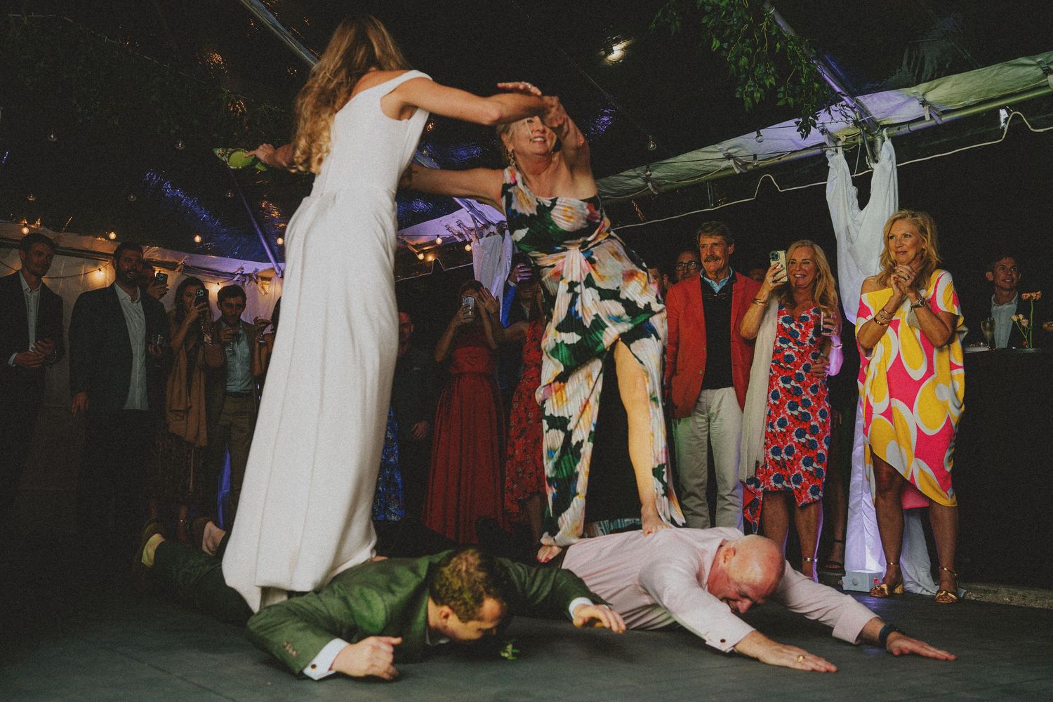 Bride and wedding guests dancing energetically at an outdoor evening wedding reception party.