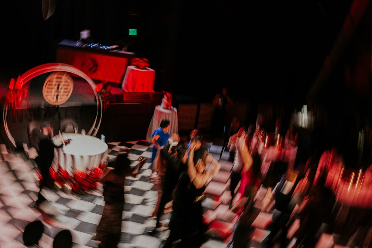 Blurred motion shot of a lively event with checkered dance floor, red lighting, and HP branded stage.