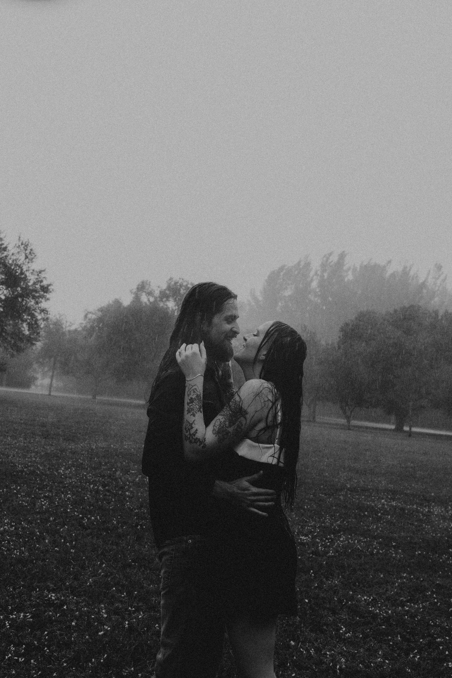 A couple embraces in a foggy field on a misty morning creating a romantic silhouette against the landscape.