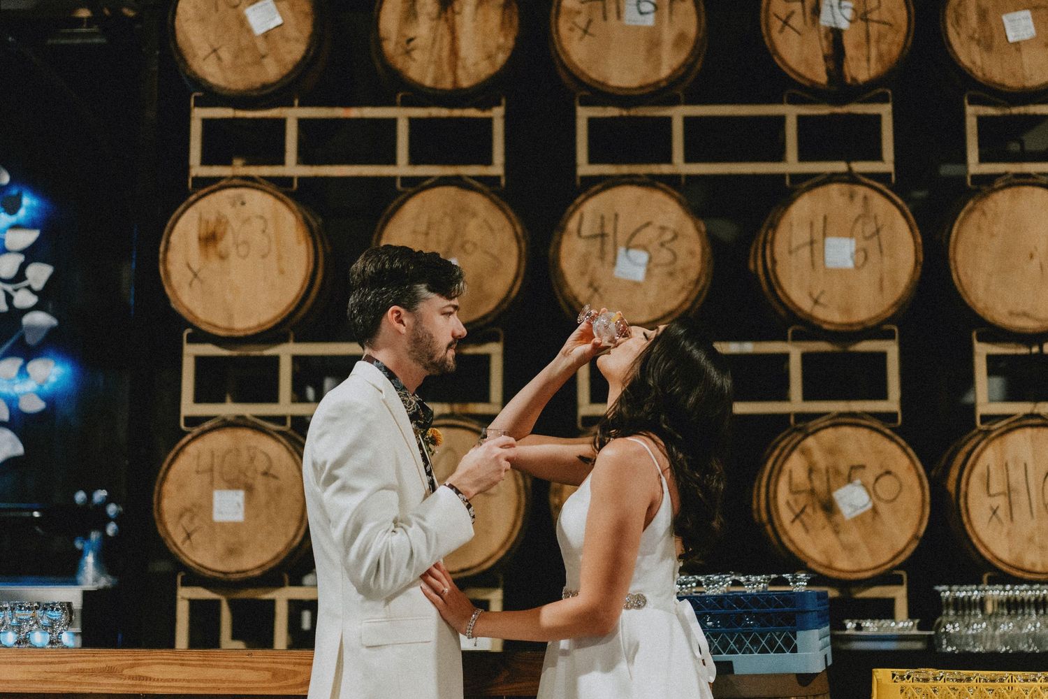 Couple sharing a romantic moment in front of wooden barrels at a winery wedding venue.