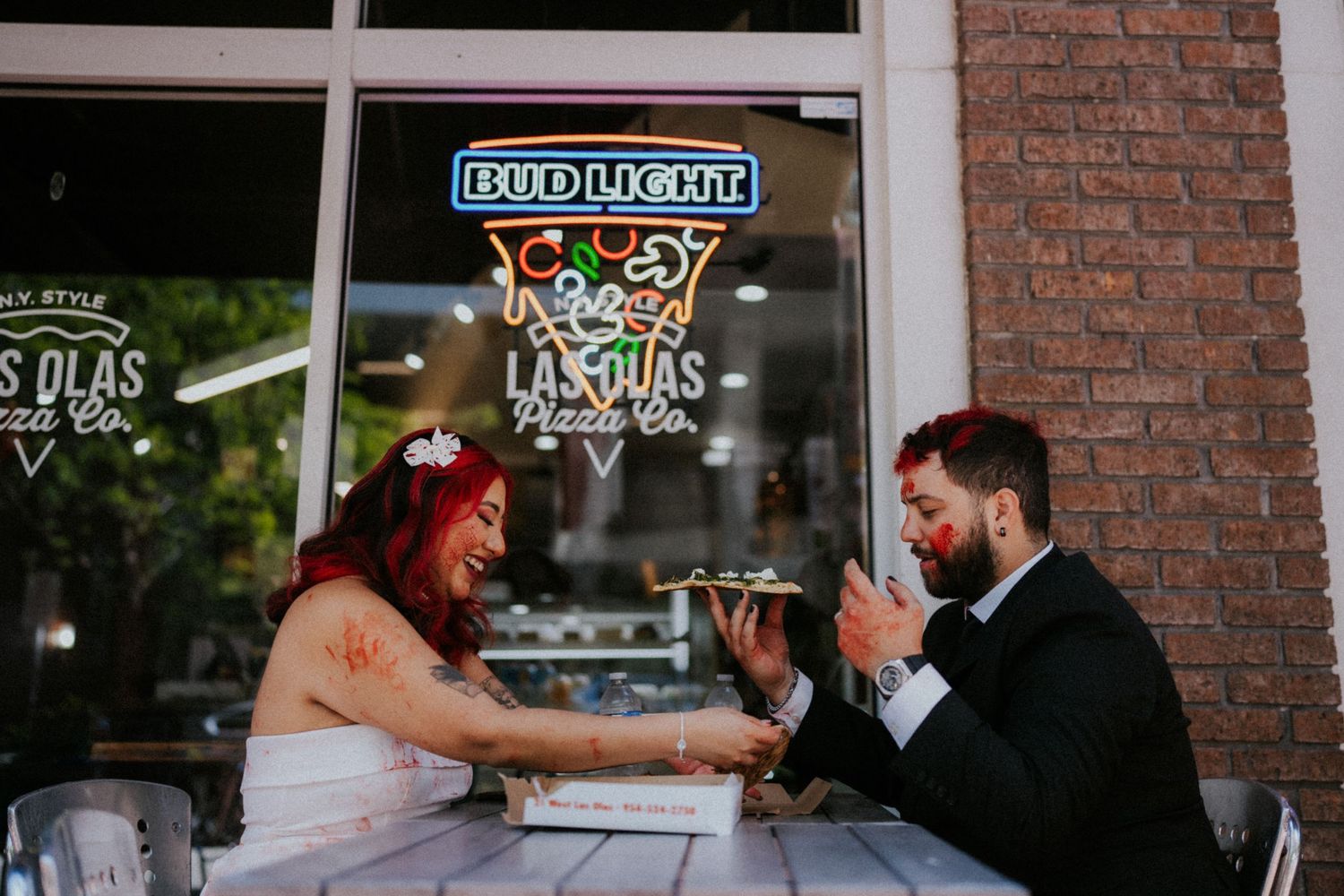 Bride and groom share a laugh while eating pizza at Las Olas Pizza Co. on their wedding day.