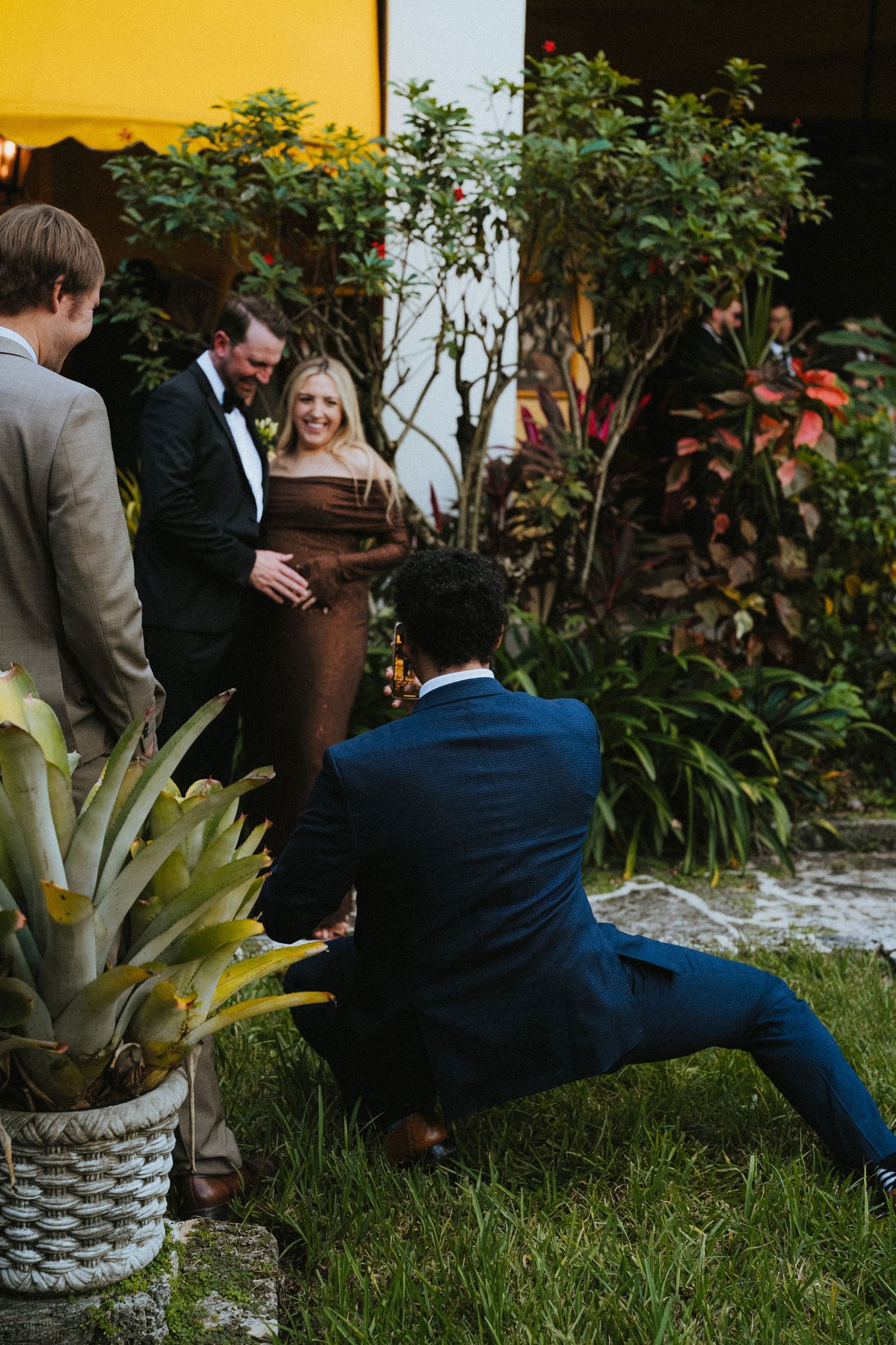 Wedding guests mingle and laugh outdoors in a tropical garden setting during a elegant wedding reception.