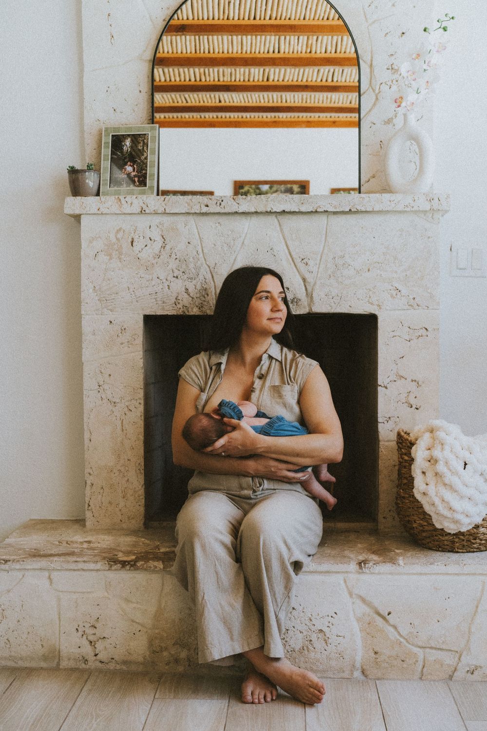 A series of four intimate photographs showing a mother nursing her baby while sitting by a rustic fireplace.