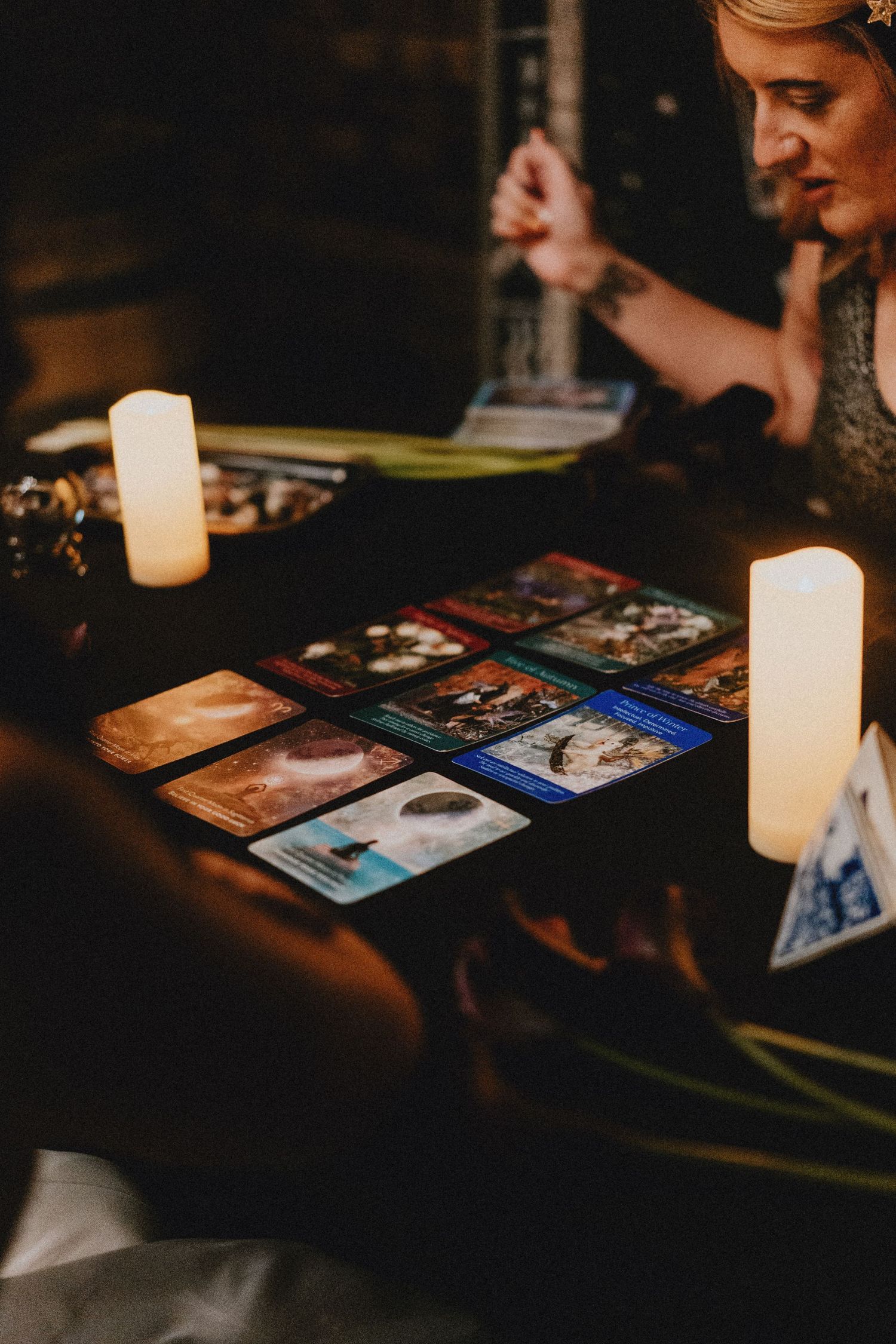 Tarot card reading by candlelight at a moody, dimly lit wedding reception table with spread cards.
