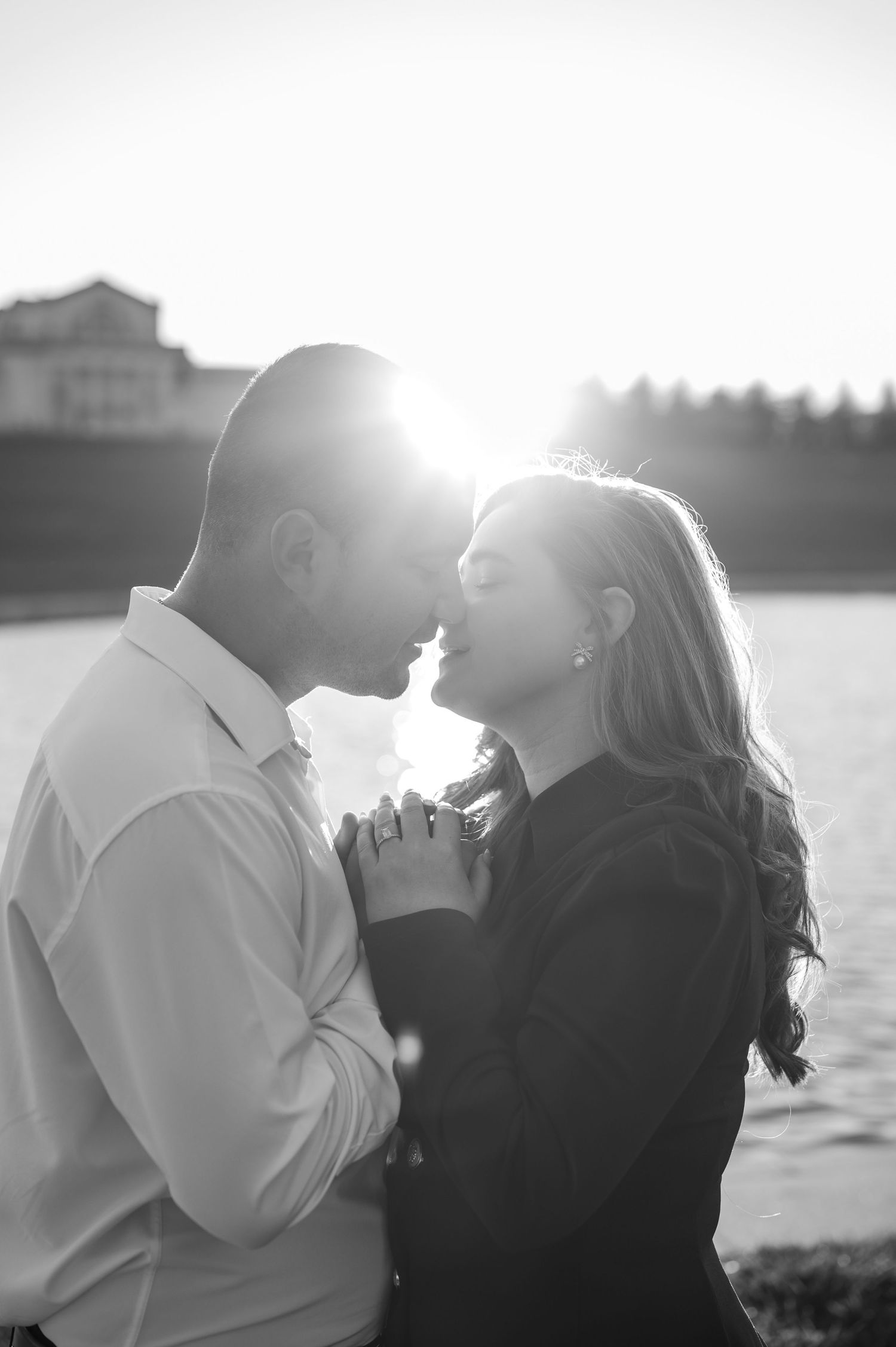 Silhouetted couple sharing an intimate moment by the water during golden hour.