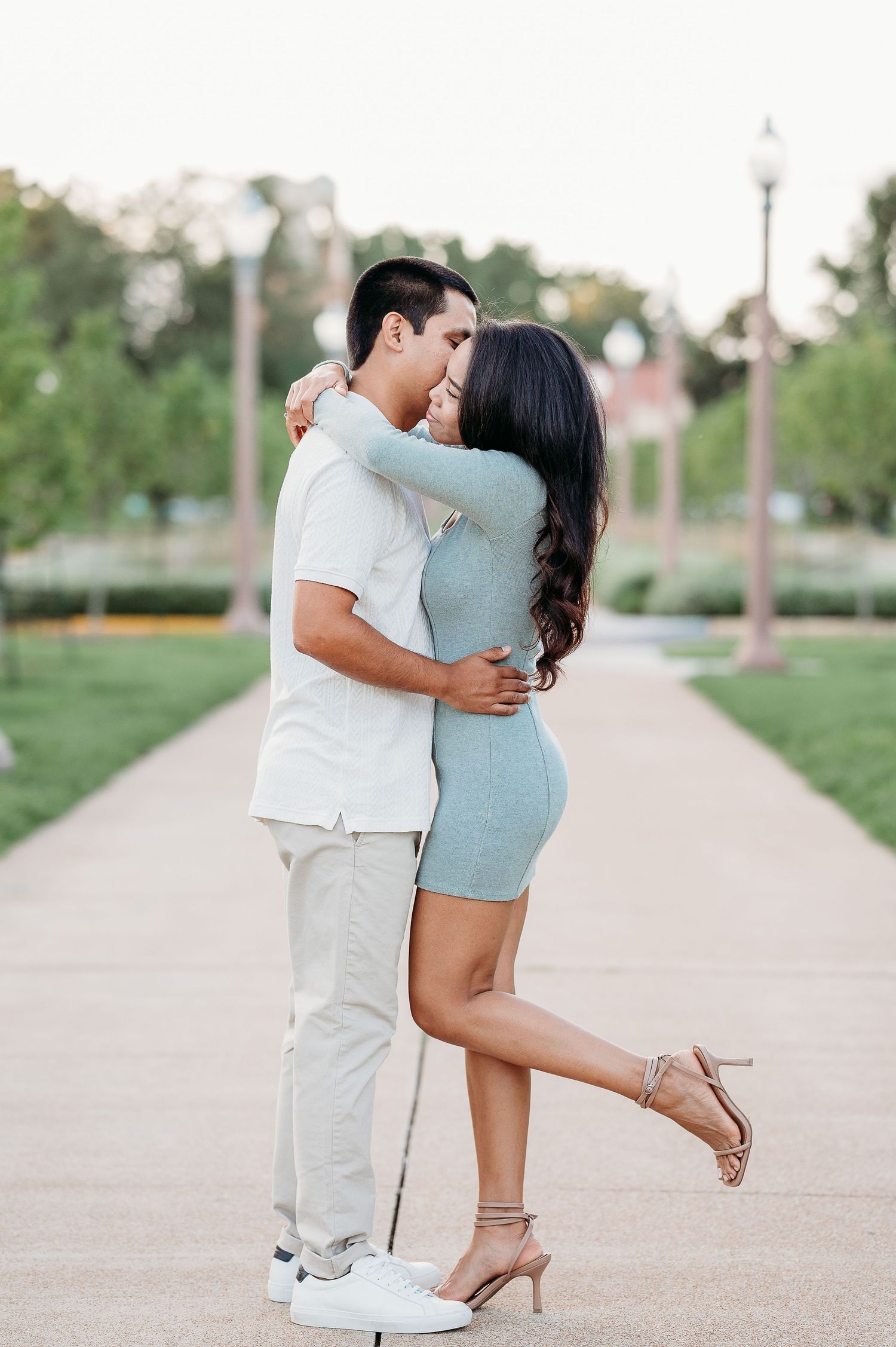 Romantic couple sharing tender moments on a paved walkway at sunset.