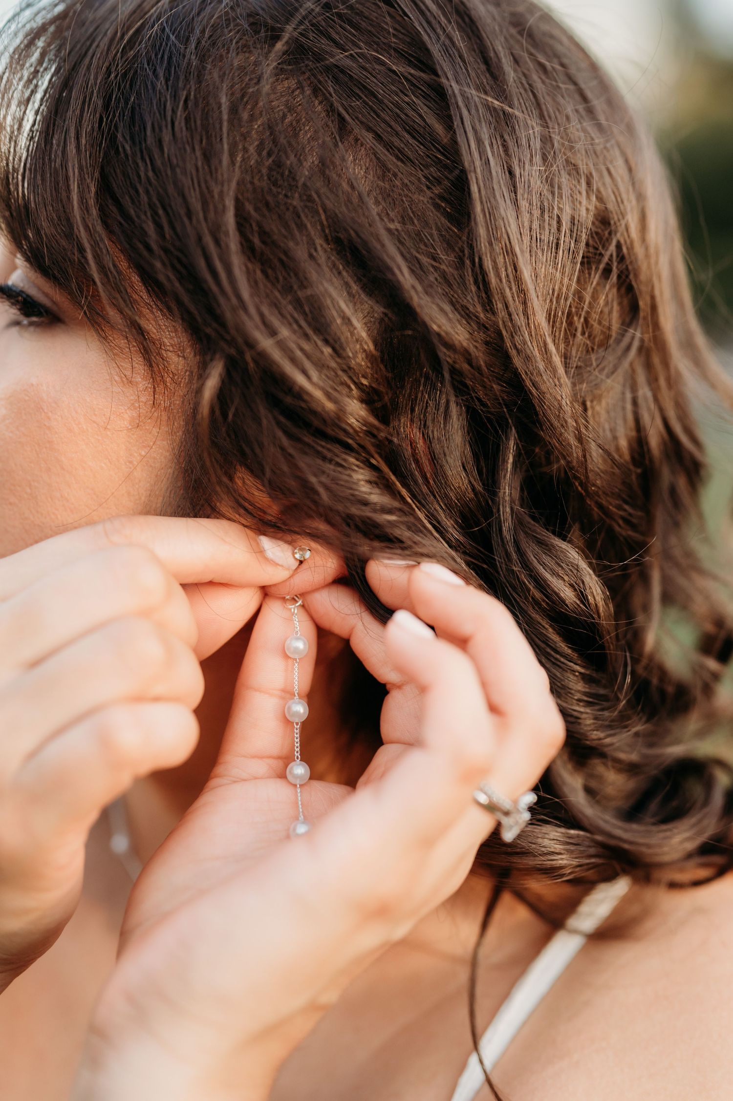 Close-up of earrings being fastened during wedding preparations.