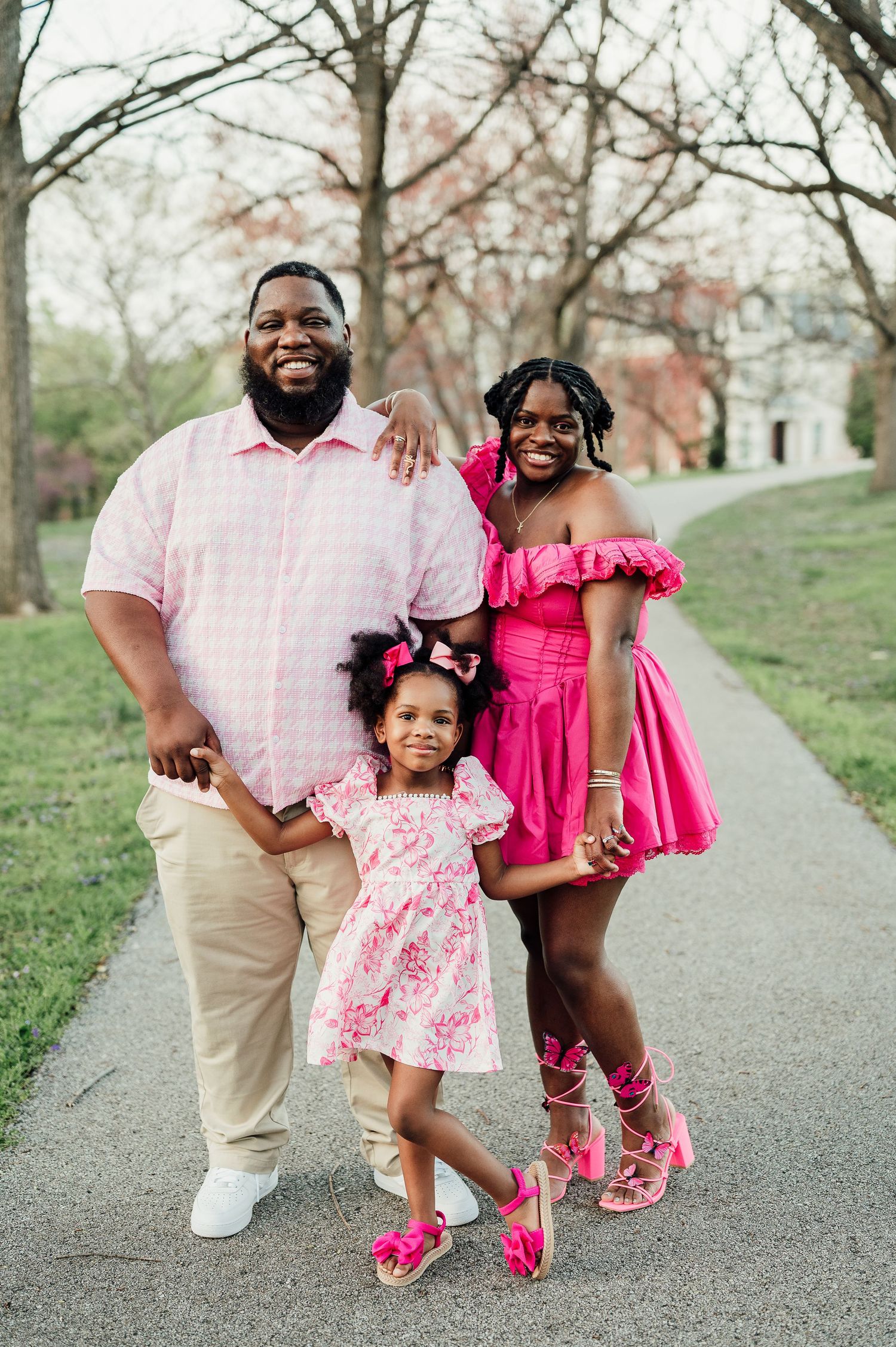 Family dressed in pink and khaki poses together on spring walkway.