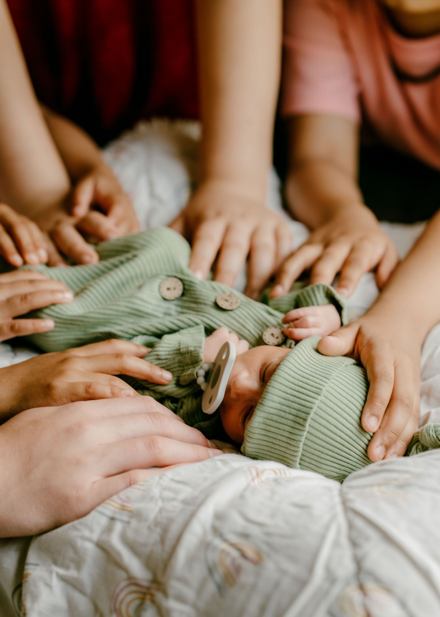 Gentle hands button up a soft mint green outfit during newborn care.