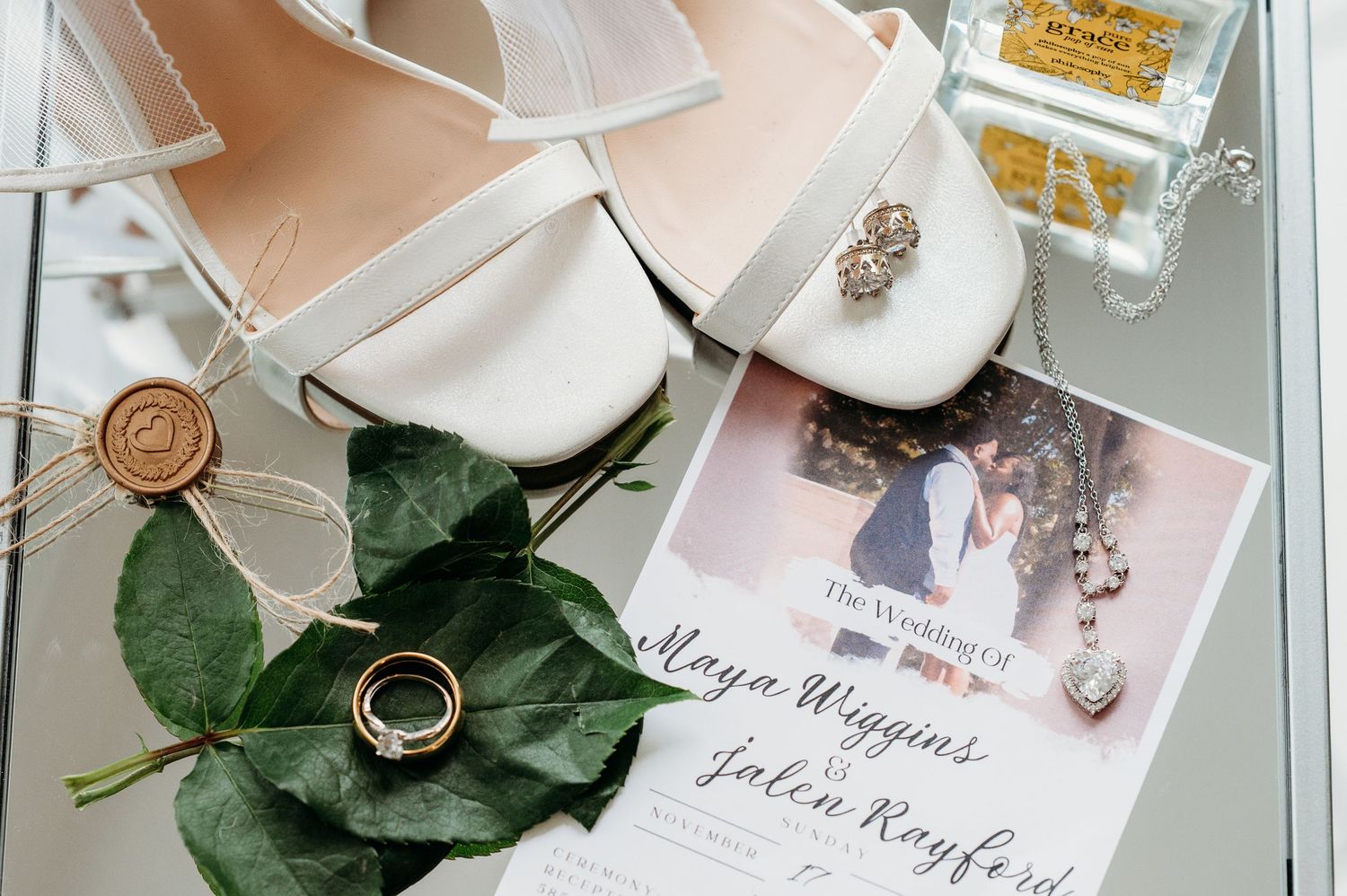 Flat lay with jewelry details and floral elements arranged on a white surface alongside elegant wedding rings. Taken by Jessica Sagerty