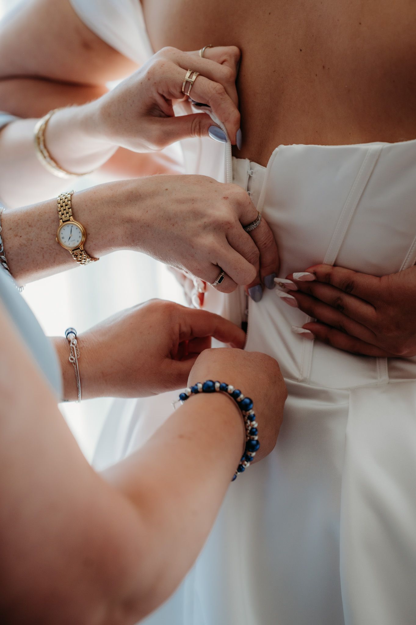 Close-up of hands adjusting white wedding dress with jewelry details.