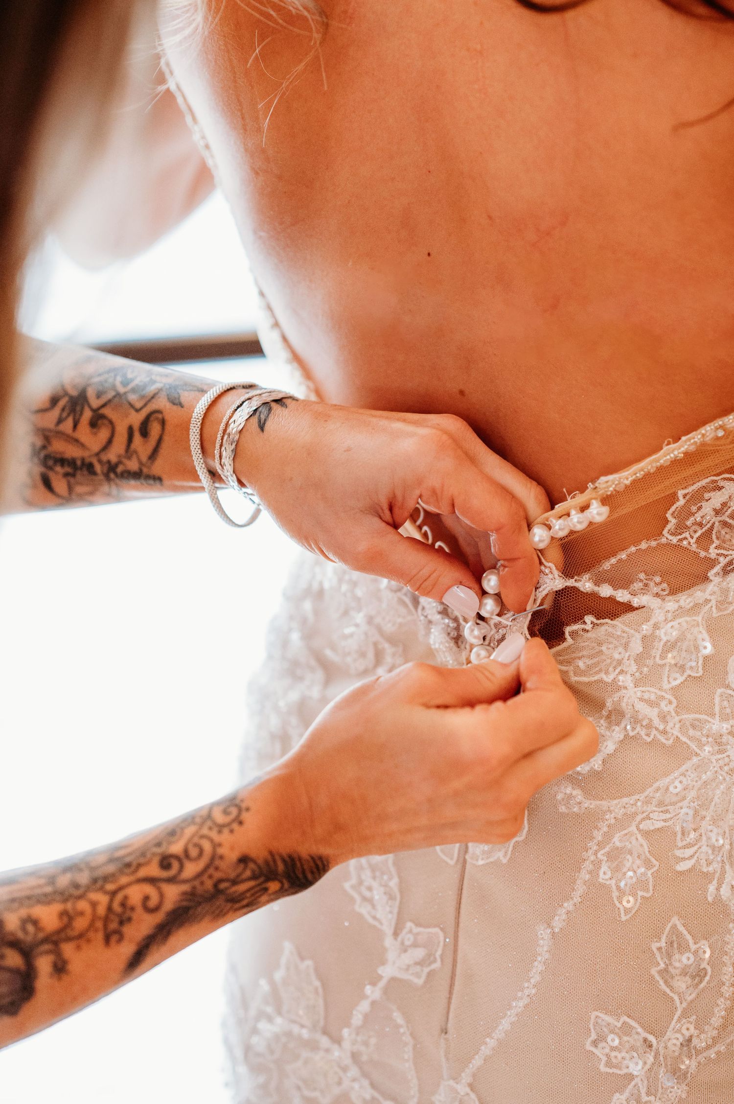 Close-up sequence of hands adjusting buttons and lace details on a bridal gown.