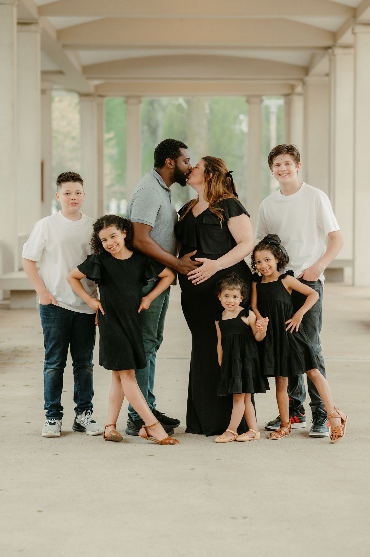 Creative family photo with coordinated black outfits in an architectural setting.