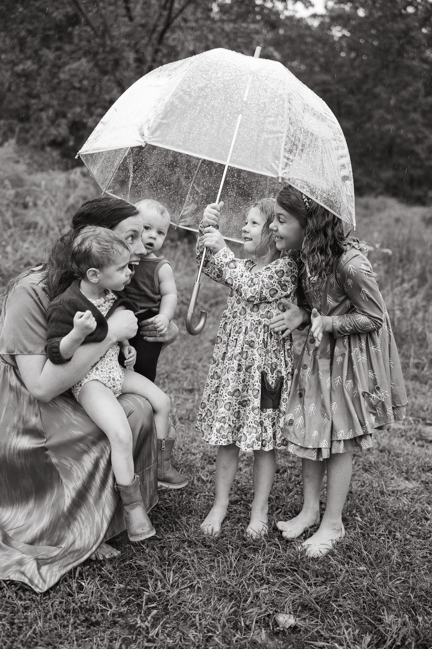 Jessica Sagerty with her kids interacting under a clear umbrella outdoors.