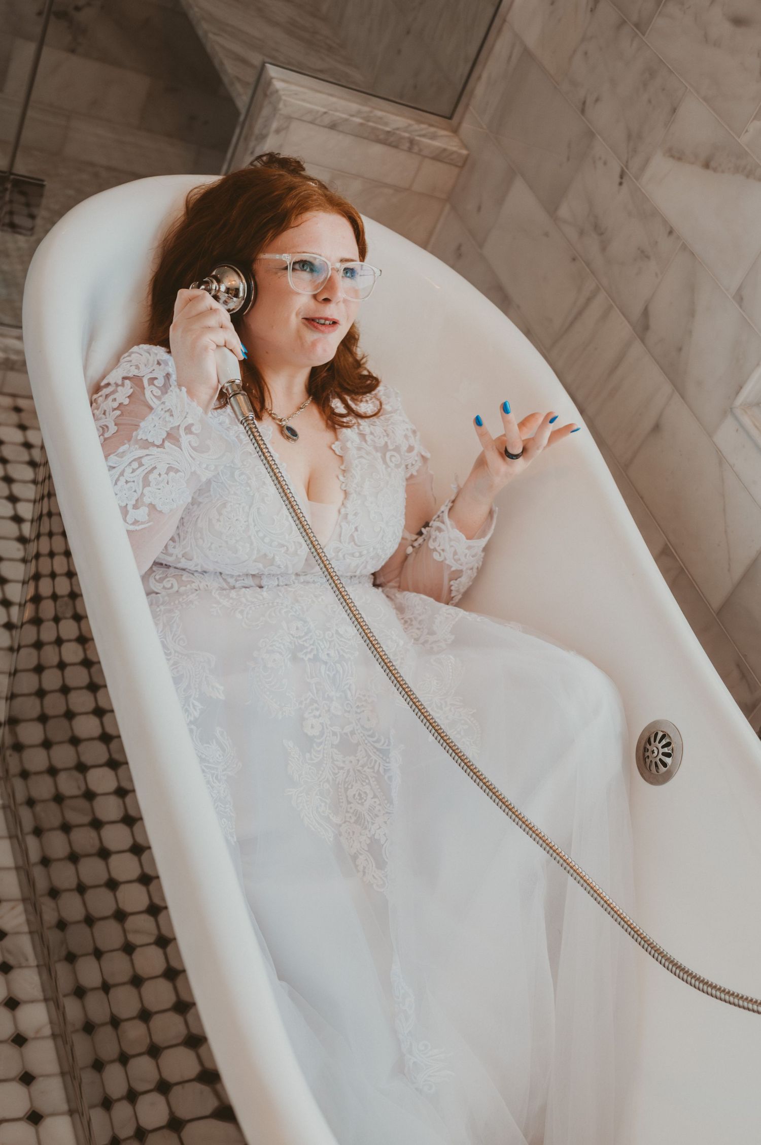 Elegant white lace wedding dress details photographed in a classic bathtub setting.