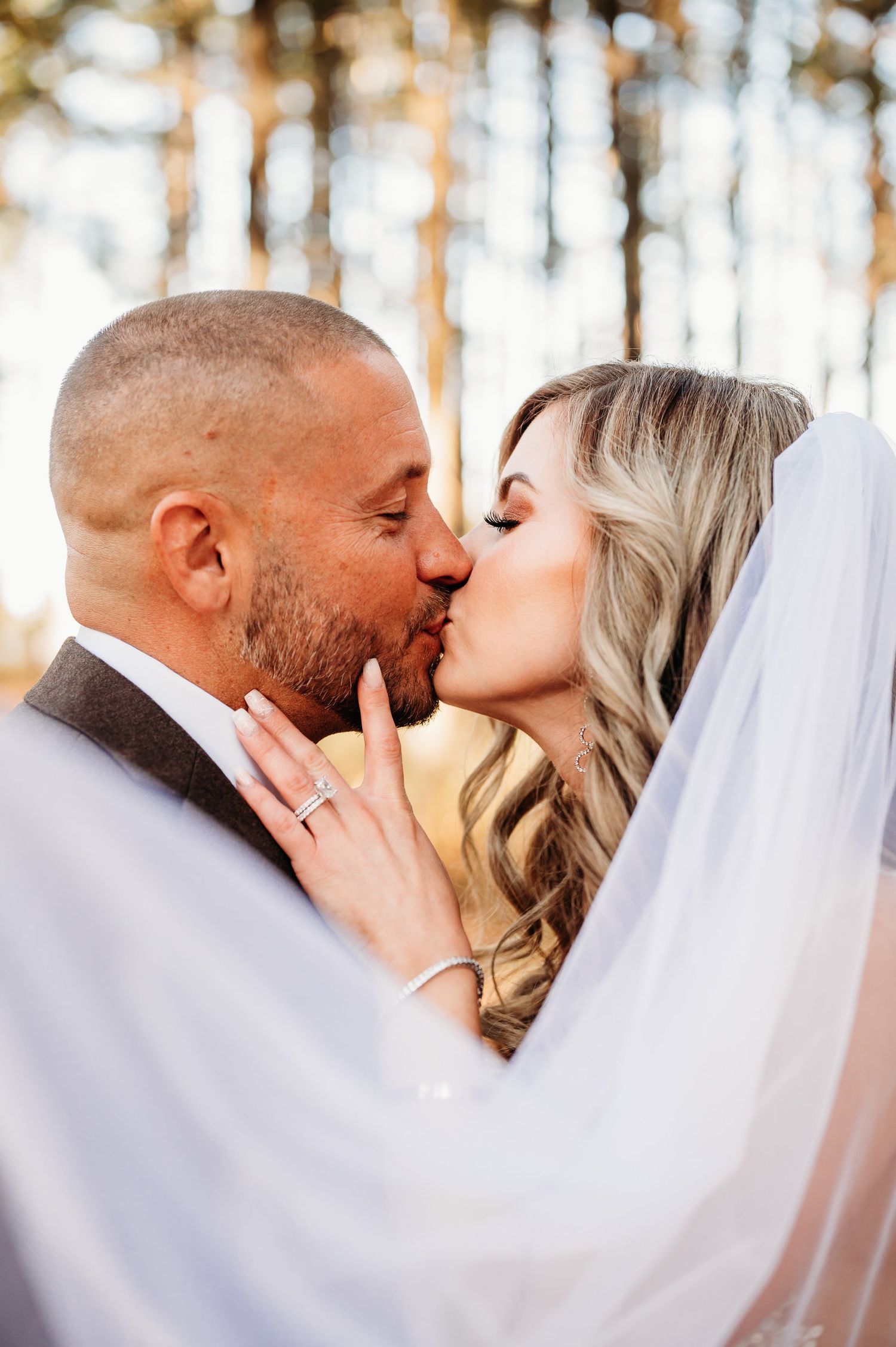 Romantic veil-covered kiss sequence in a sunlit forest setting.